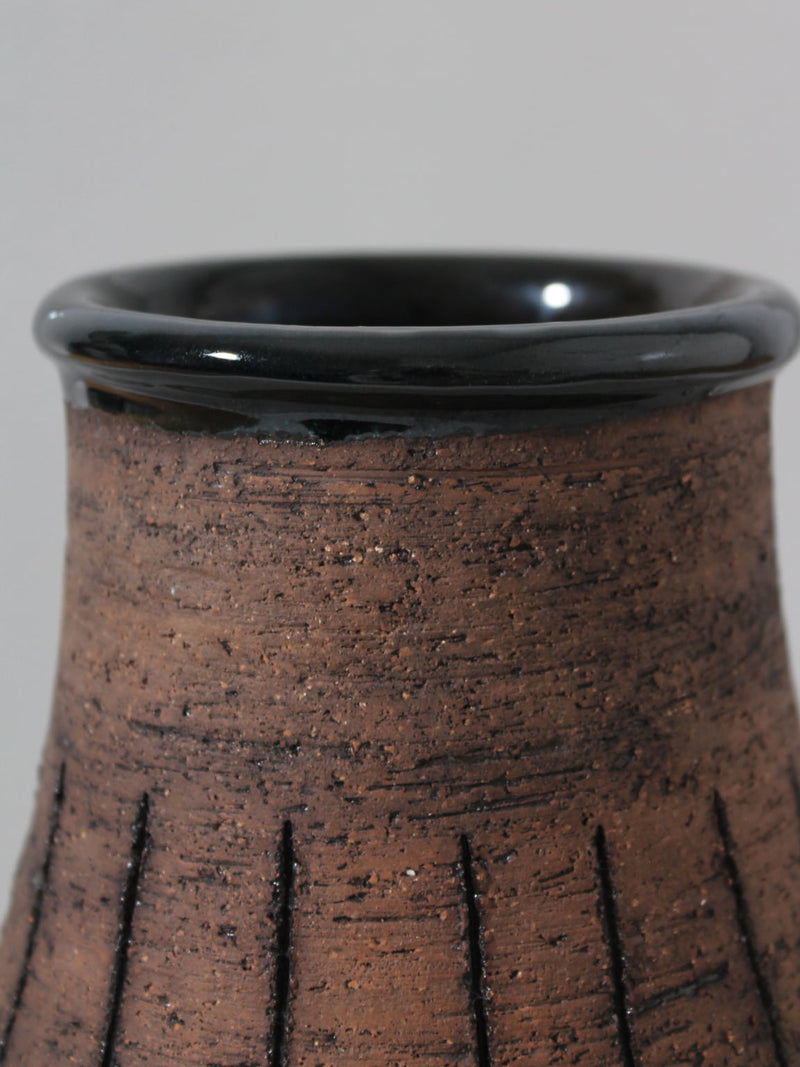 Close-up of the top of an Eke Bjerén Ceramic Vase on Legs for Gabriel Sweden, 1960s by Vintage Stories, featuring a textured grooved surface and glossy black rim, set against a plain light gray background.
