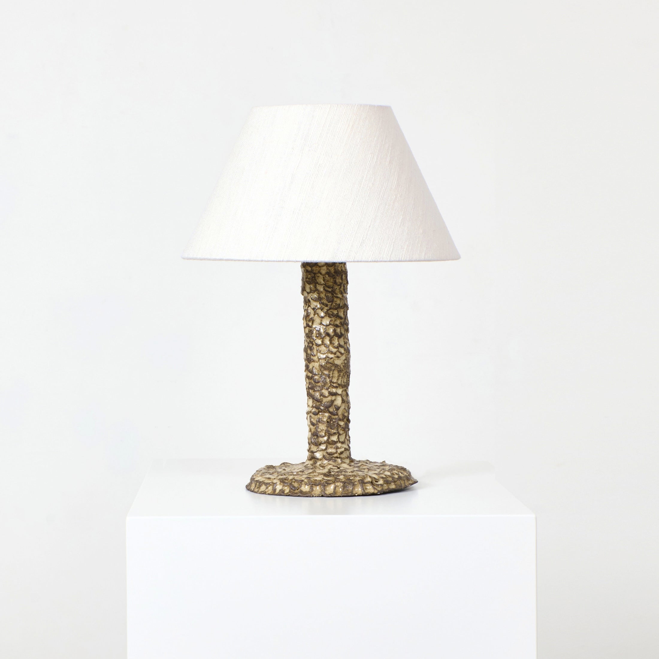 Casa Bedside Light — angled view on white pedestal with textured base