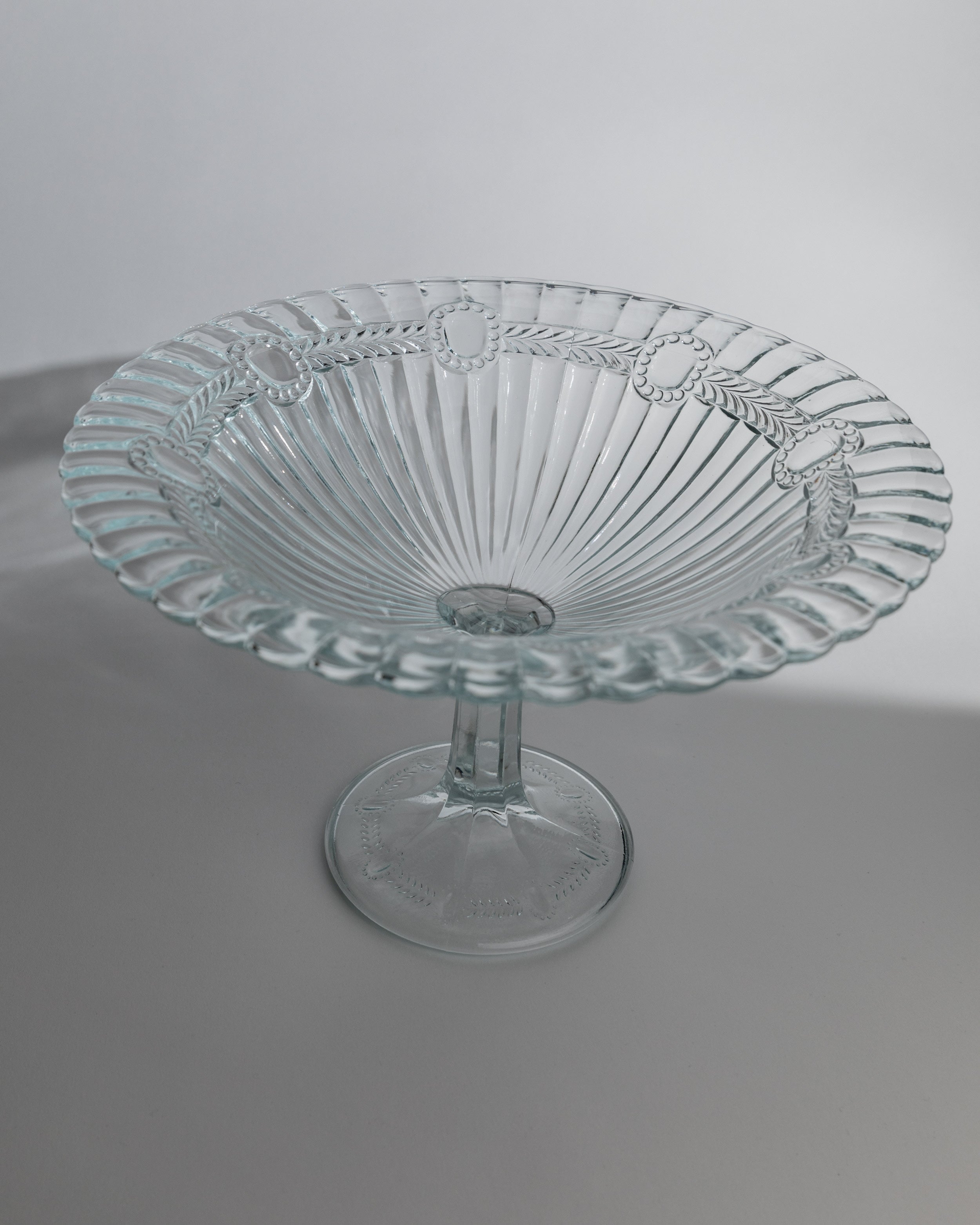 Clear glass pedestal serving dish with radial ribbed pattern and scalloped rim from 1910s Poland