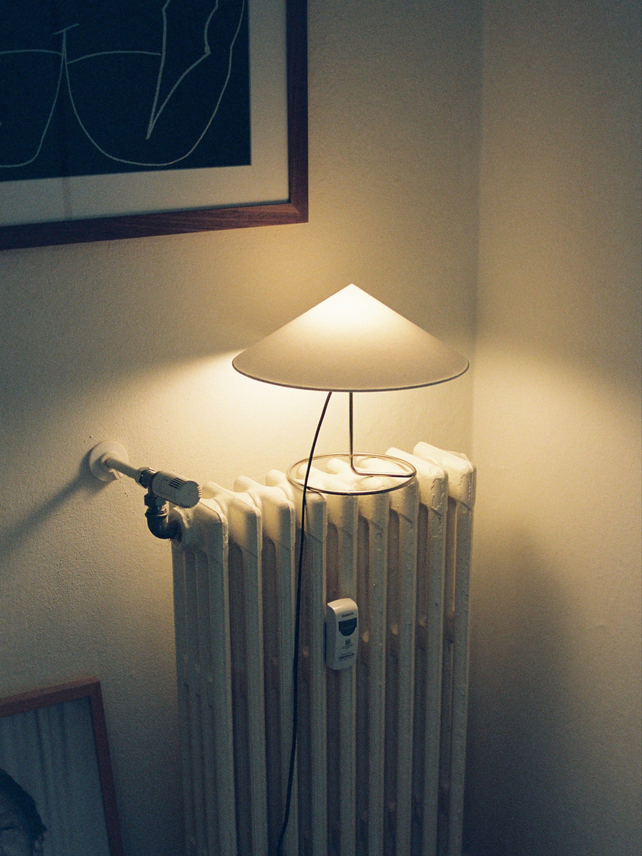 Douli Table Lamp — modern design on white radiator in cozy setting