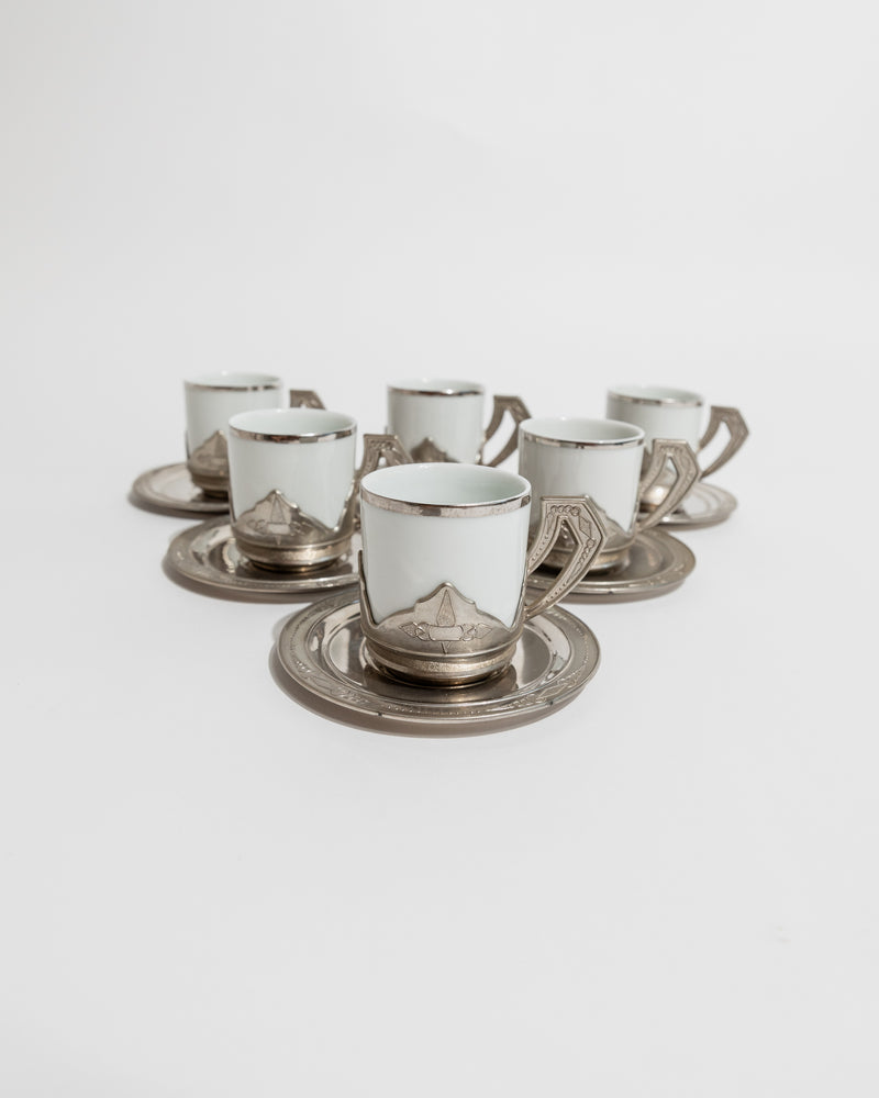 Six vintage Italian coffee cups with silver holders arranged on matching saucers