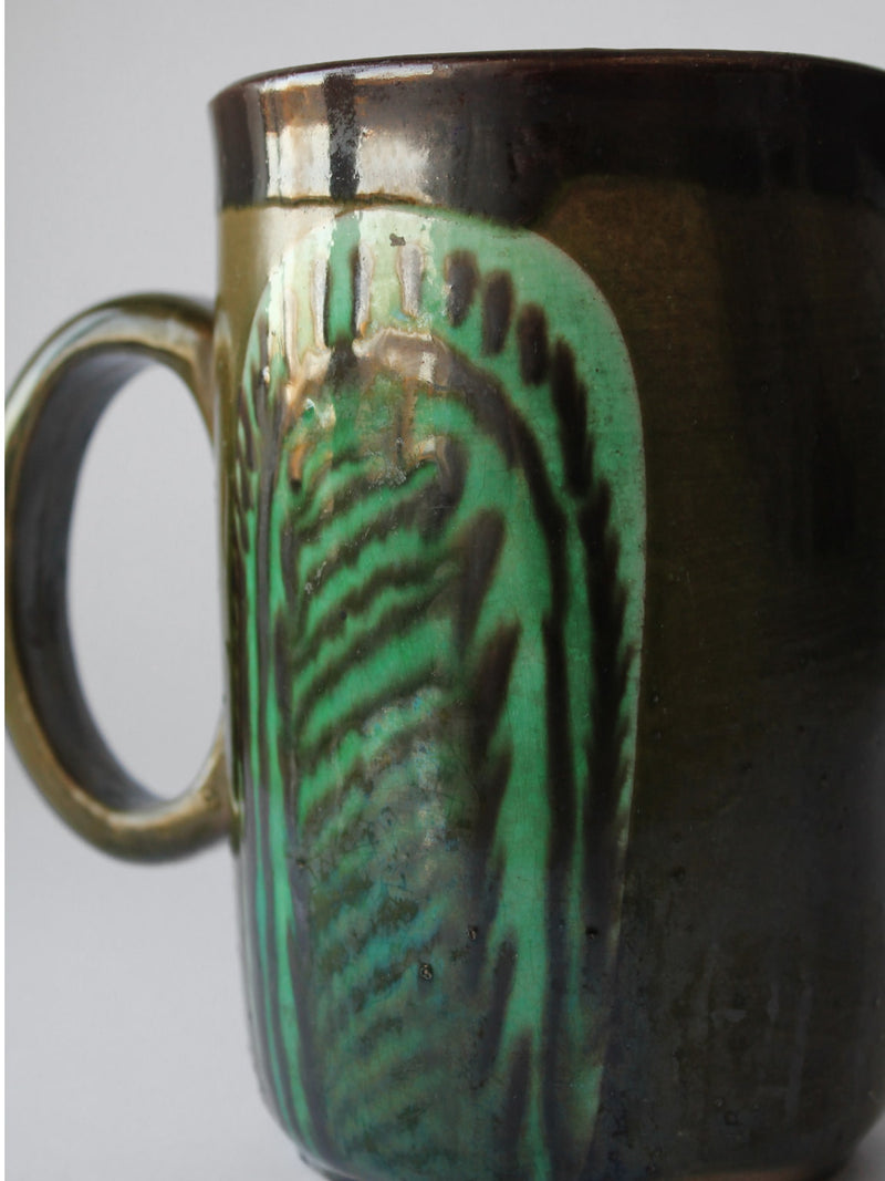 Green glazed ceramic pitcher showing detailed surface texture and drip patterns