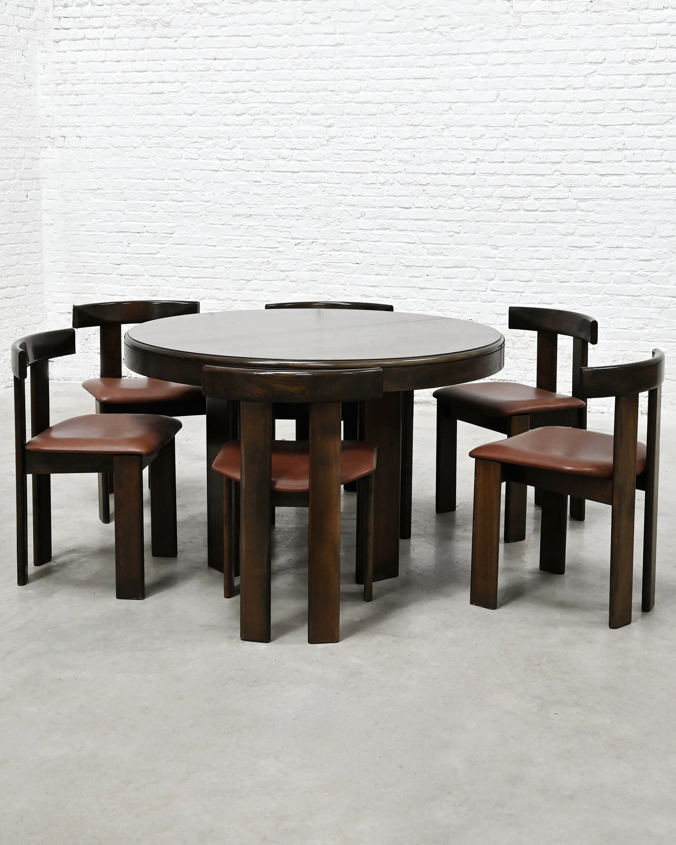 Round walnut dining table with six leather chairs by Luigi Vaghi