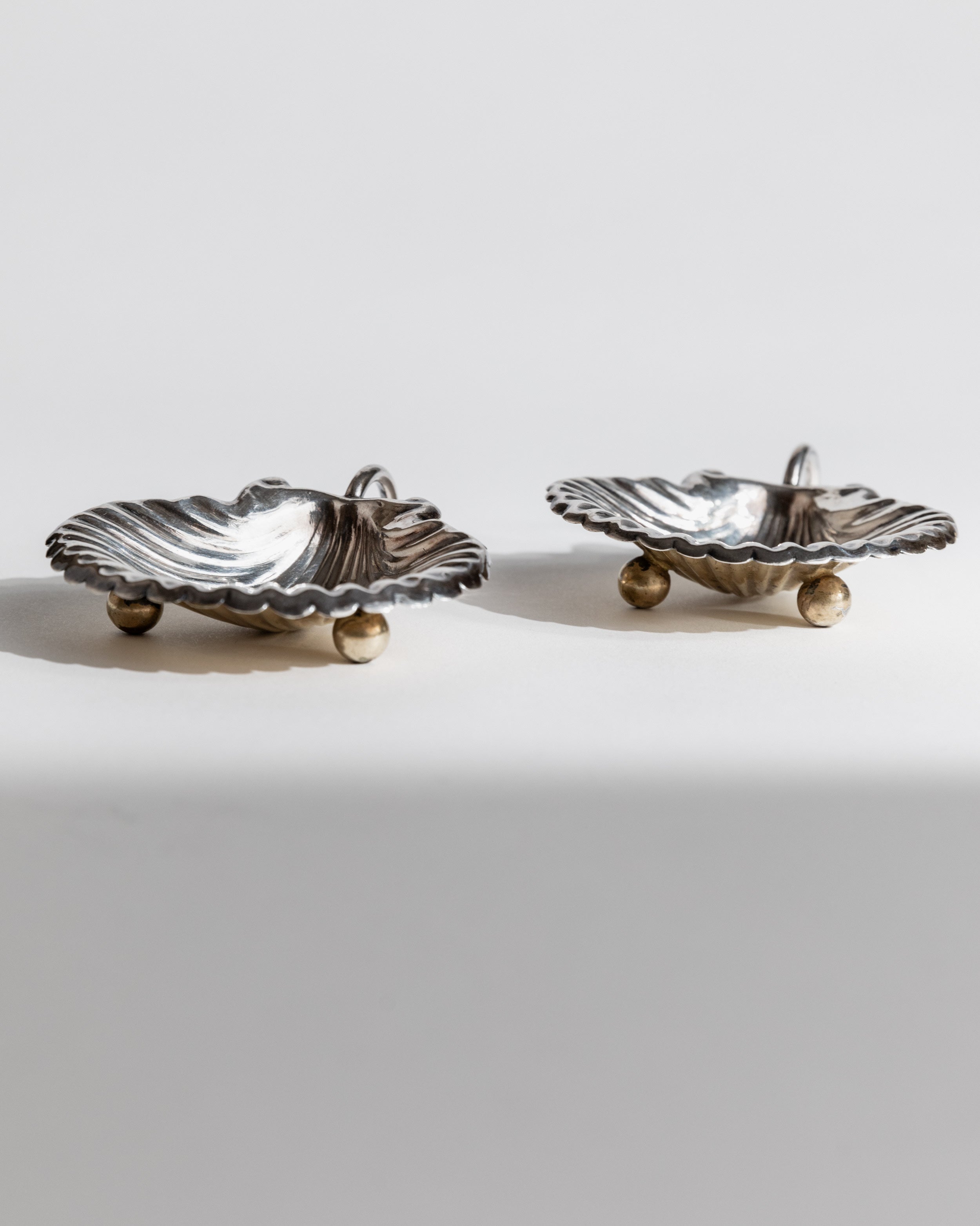 Two vintage shell-shaped silver serving bowls on bronze feet