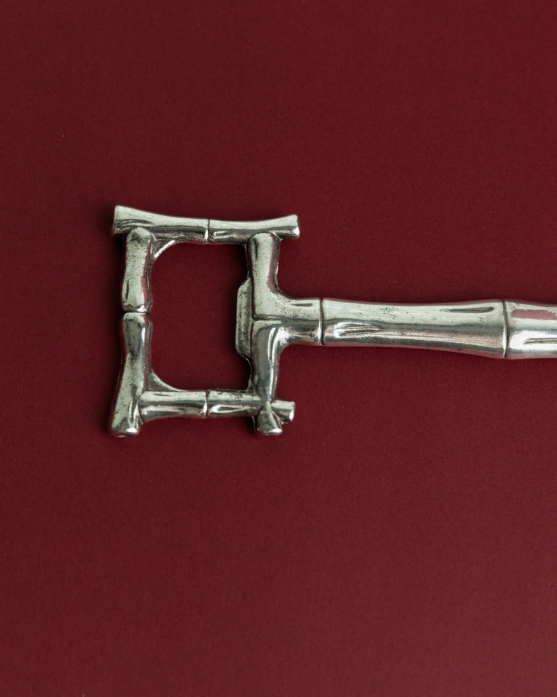 Vintage 1970s Silver Plated Bottle Opener, Bamboo Design — close-up of handle detail on red background