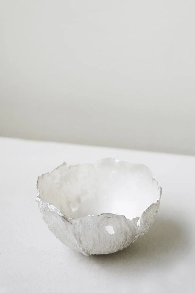 The L34 - Small Bowl in Silver by Completedworks features an organic, uneven edge in a small ceramic form, displayed elegantly on a light surface with a minimalist background.