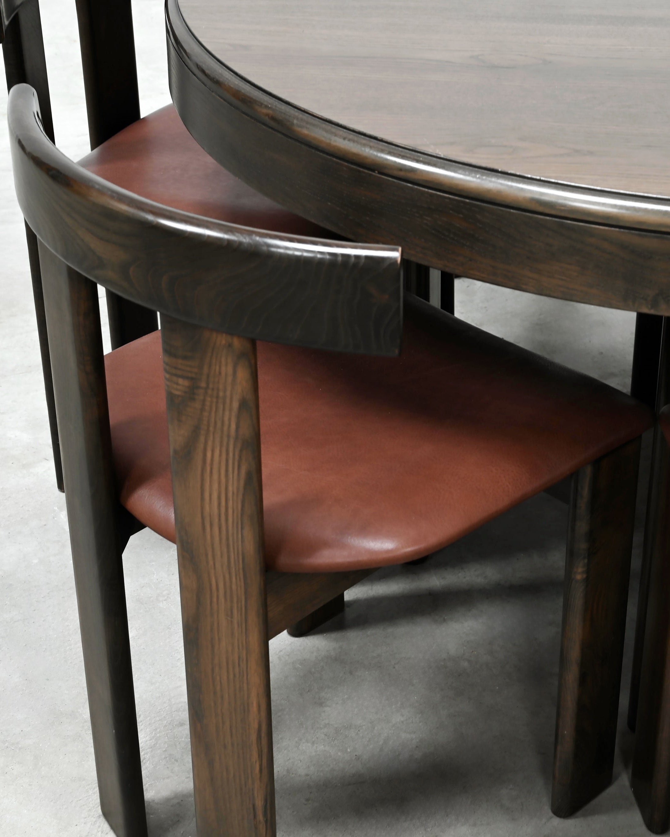 Close-up detail of curved walnut chair backs with cognac leather seats