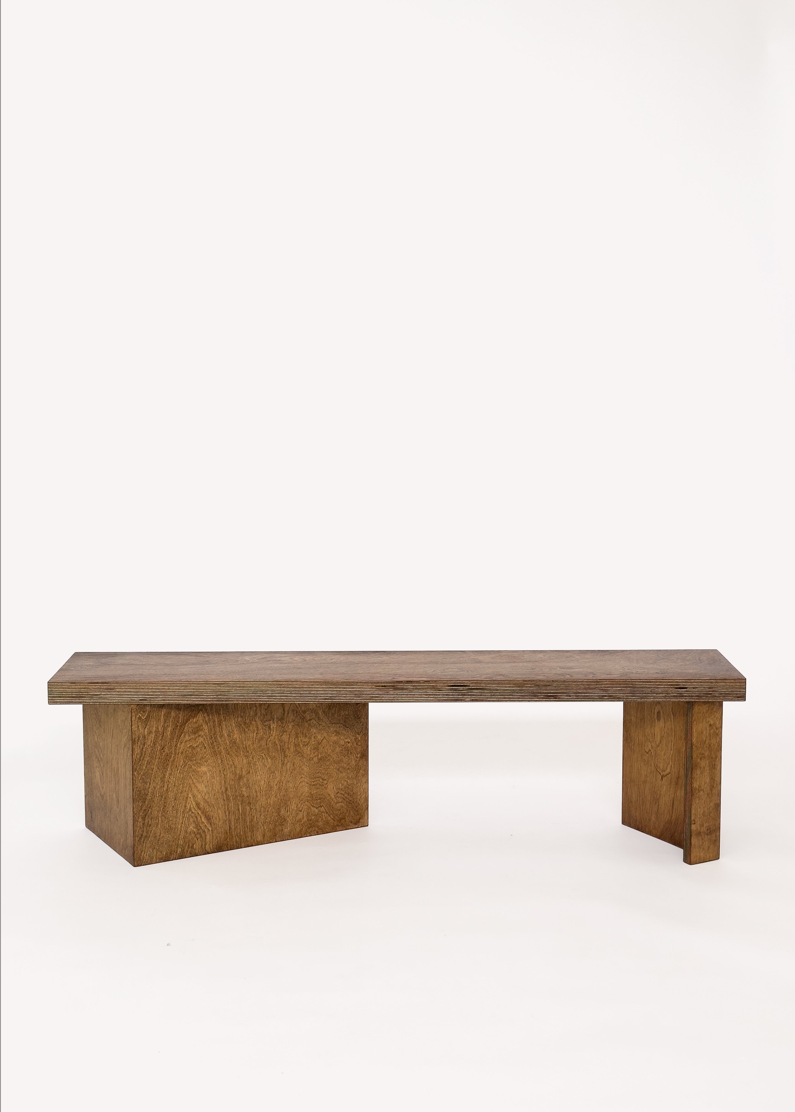 The Free plan Bench by GOONS features a minimalist rectangular seat with two asymmetrical block legs, showcasing modern architectural design from GOONS against a plain white background.