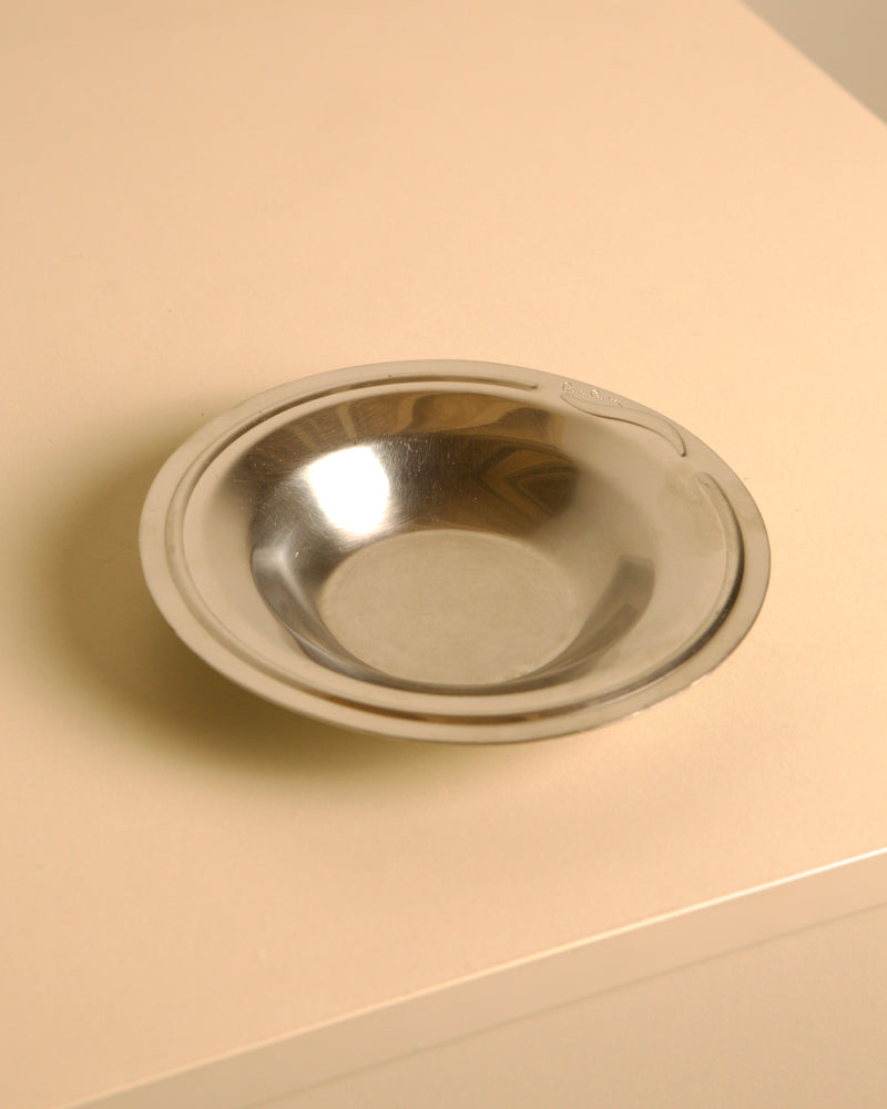 Circular stainless steel valet tray by Pierre Cardin, 1980s — close-up of polished surface on light background