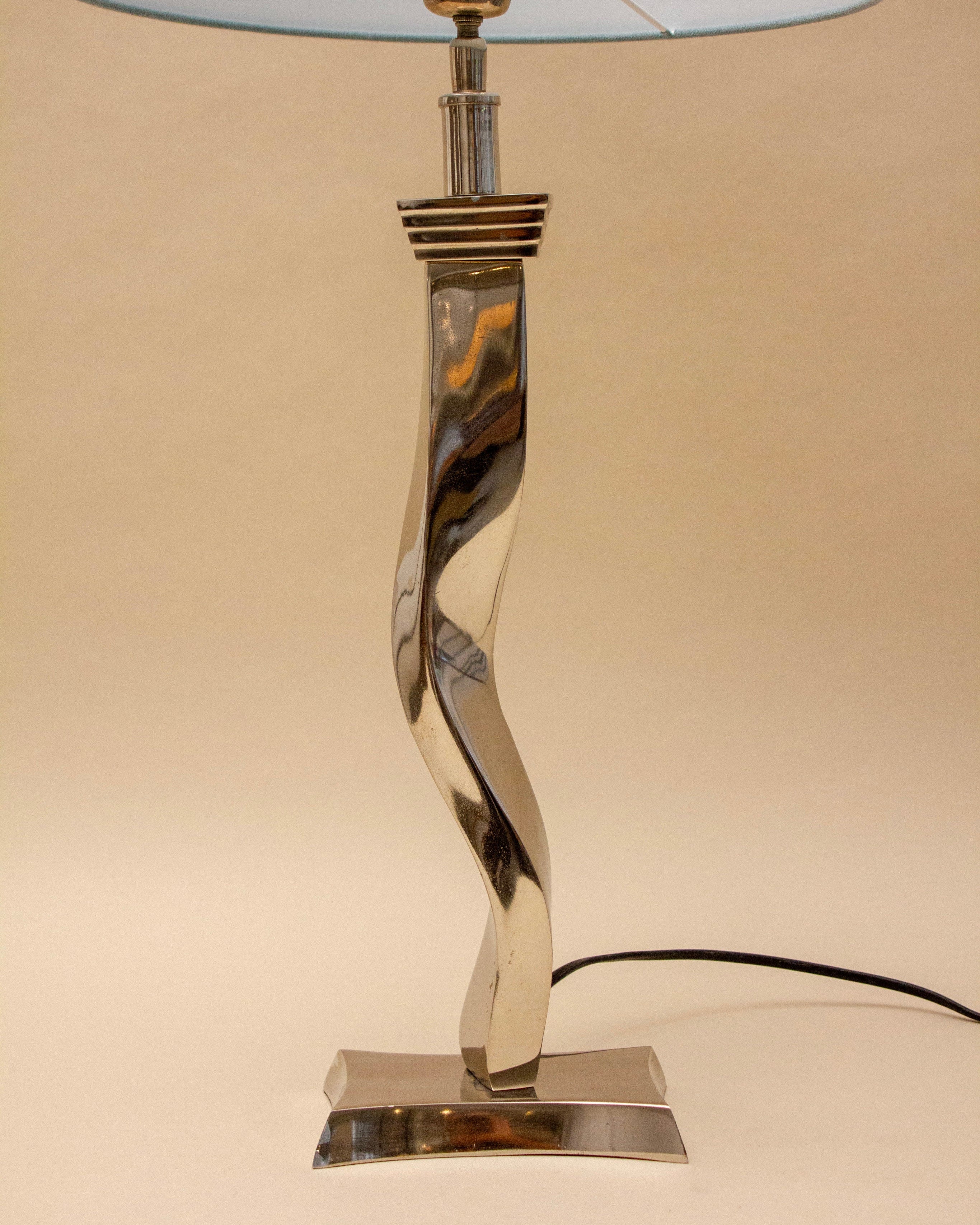 The SÒLER TAVIRA BLUE LAMP features a twisted metal base, rectangular plate, sky blue shade, and visible black power cord, shown against a plain beige background.