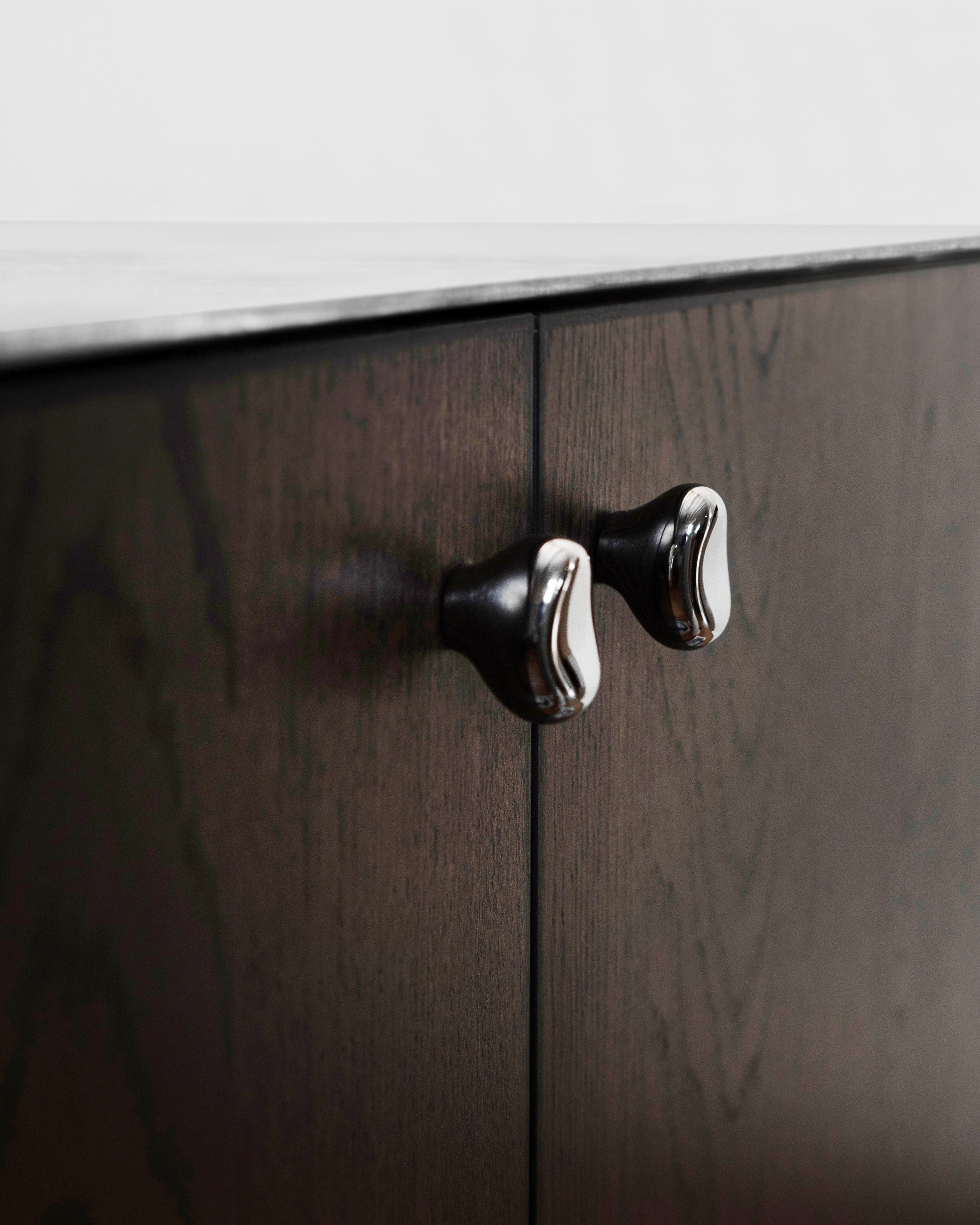 Rud Knob - Titanium — top view of knobs on dark wood cabinet