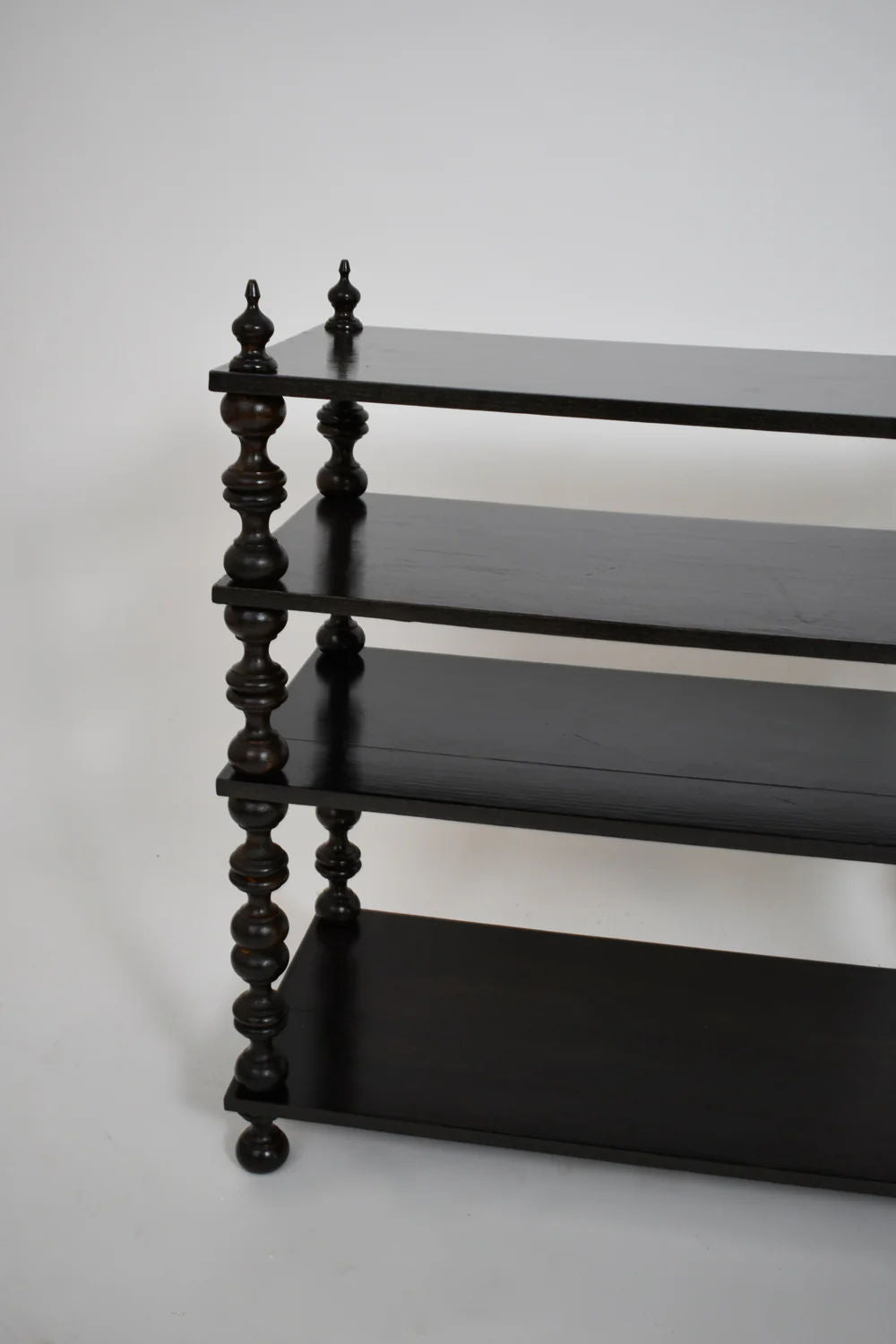 Barracuda Interiors' Ebonised Turned Wood Bookshelves Console, 1950s—four-tier dark wood shelf with spindle legs—shown against a white background; only the left half of the console is visible.