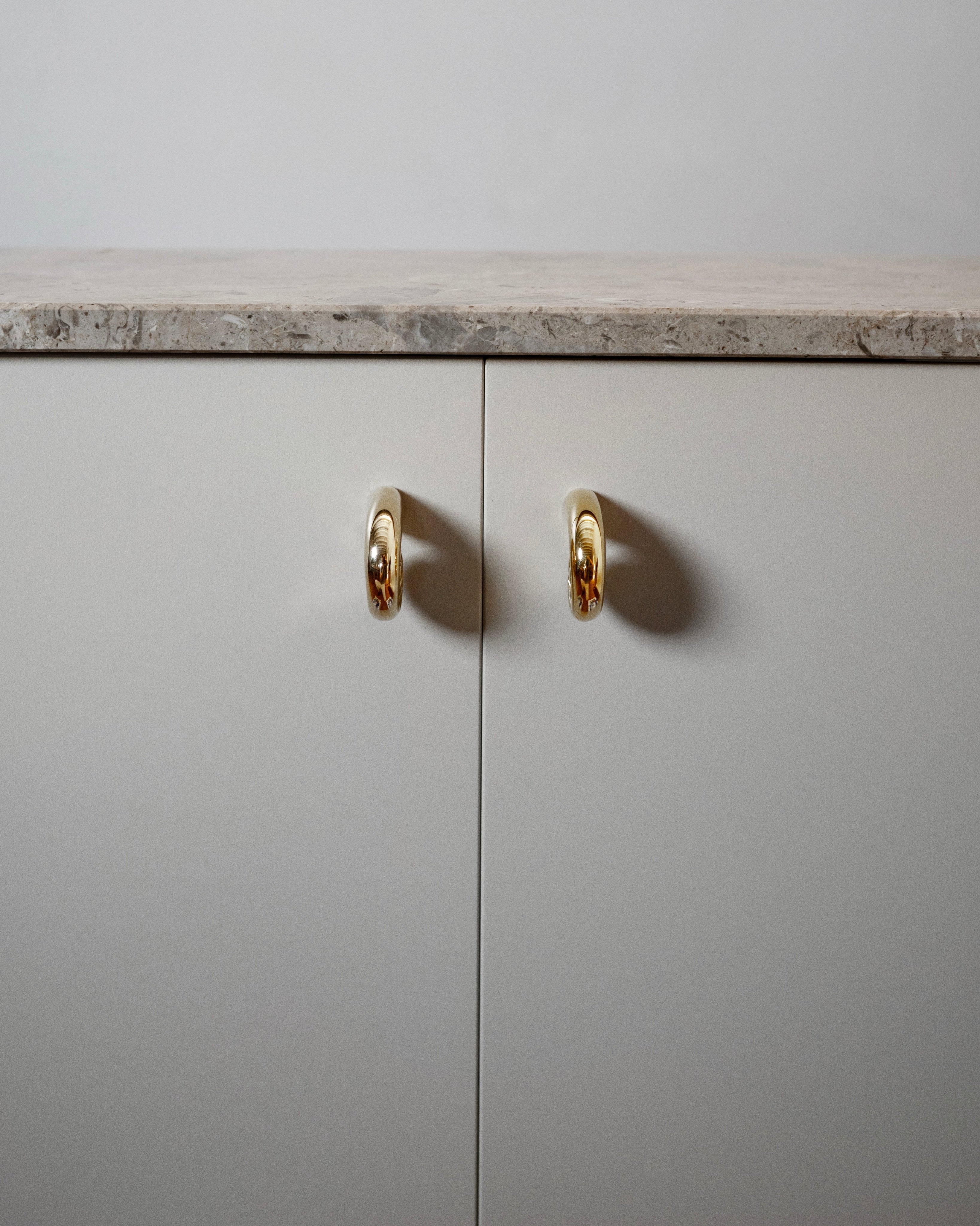 Noelle Knob - Brass — side view on light-colored cabinet