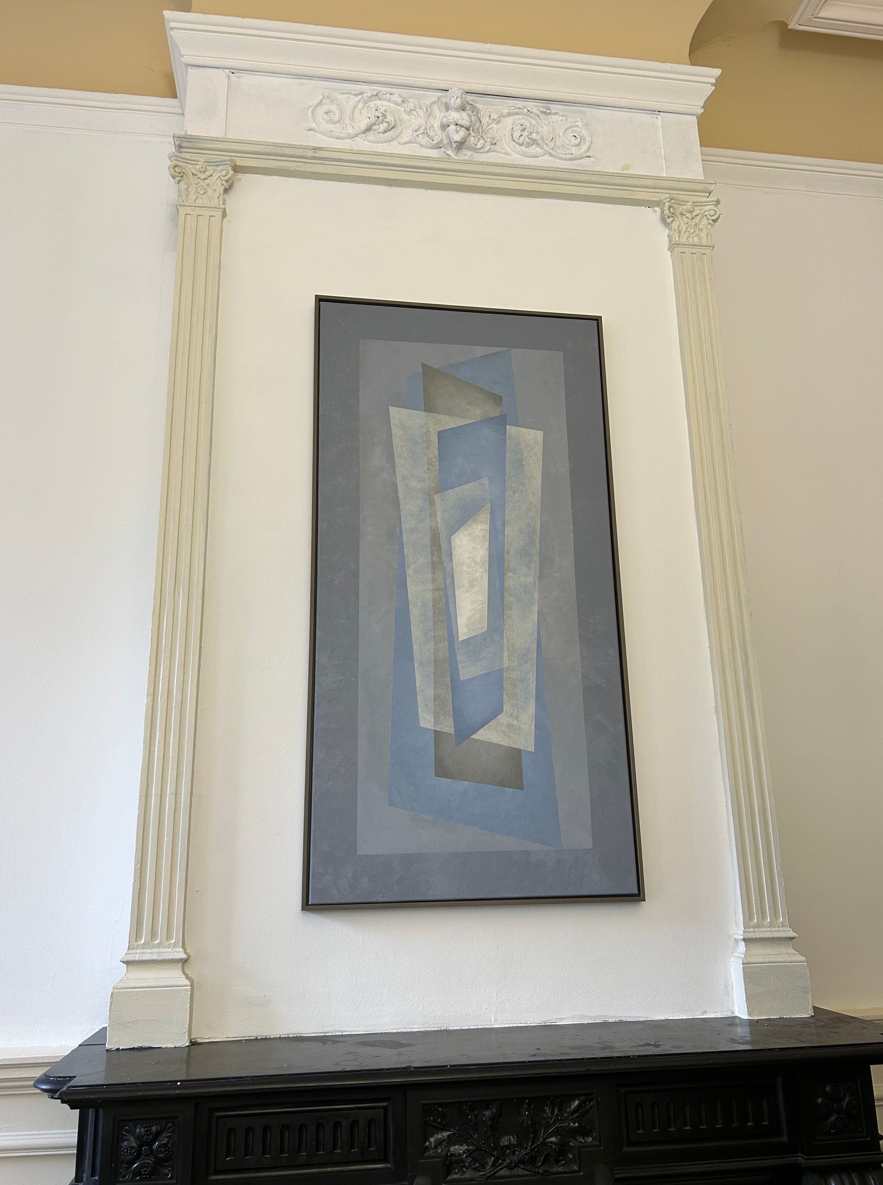 The "Floating" Painting by Iris Bavelaar, featuring abstract blue-gray overlapping rectangles, is framed and displayed on a white wall above a black ornate mantel with decorative columns and molding.