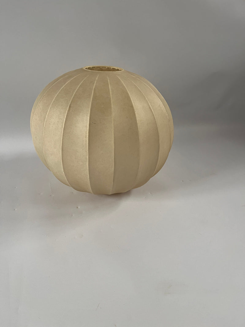 The Italian Cocoon Pendant by Achilles Castiglioni from Maud Vaughan is a round, beige pendant light with vertical ridges, shown against a plain light gray background.