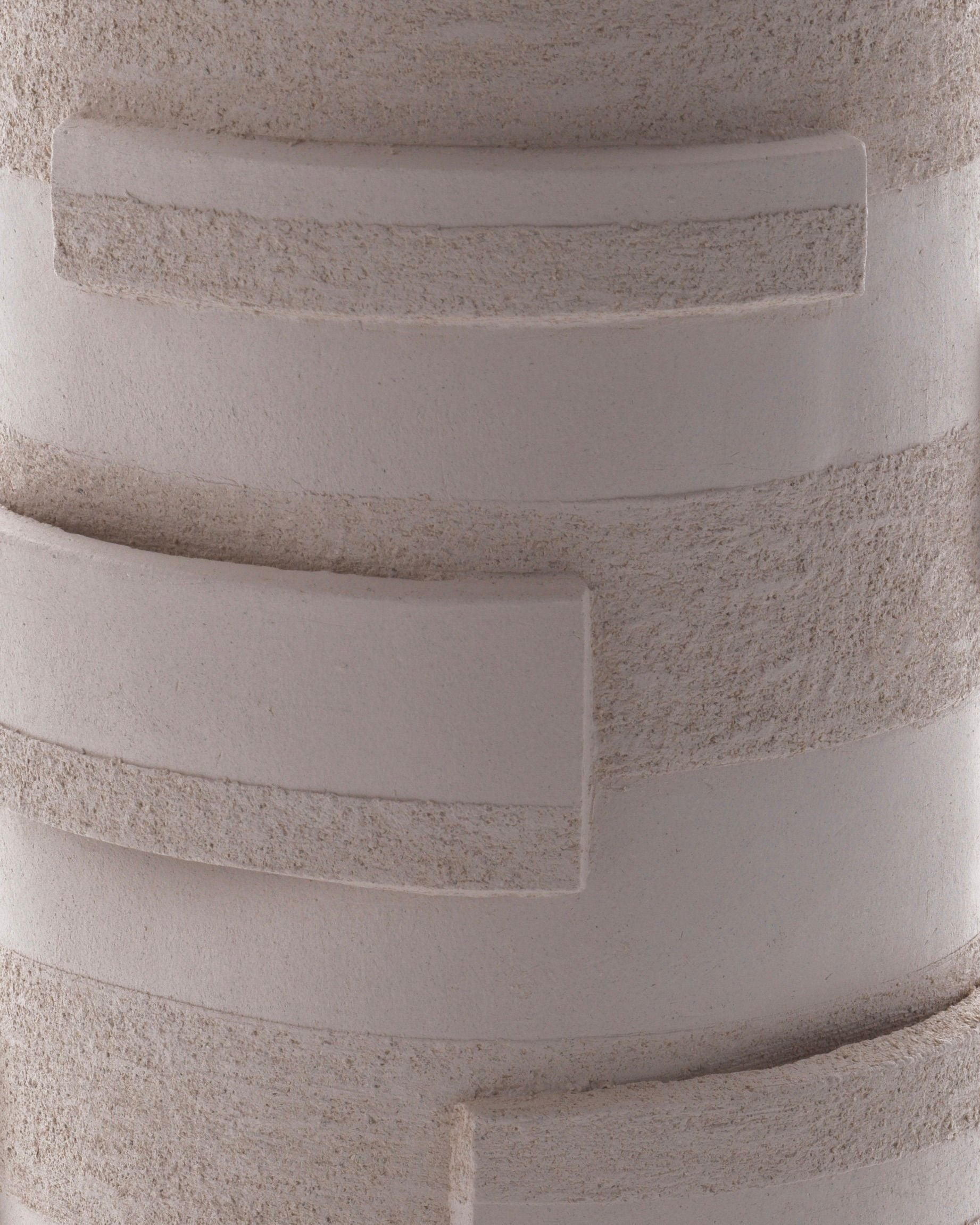 The "Bricks" Table Lamp by Katia Langeard features a textured ceramic cylindrical body with smooth and rough horizontal bands plus raised rectangles—perfect as hallway accent lighting on a light beige surface.