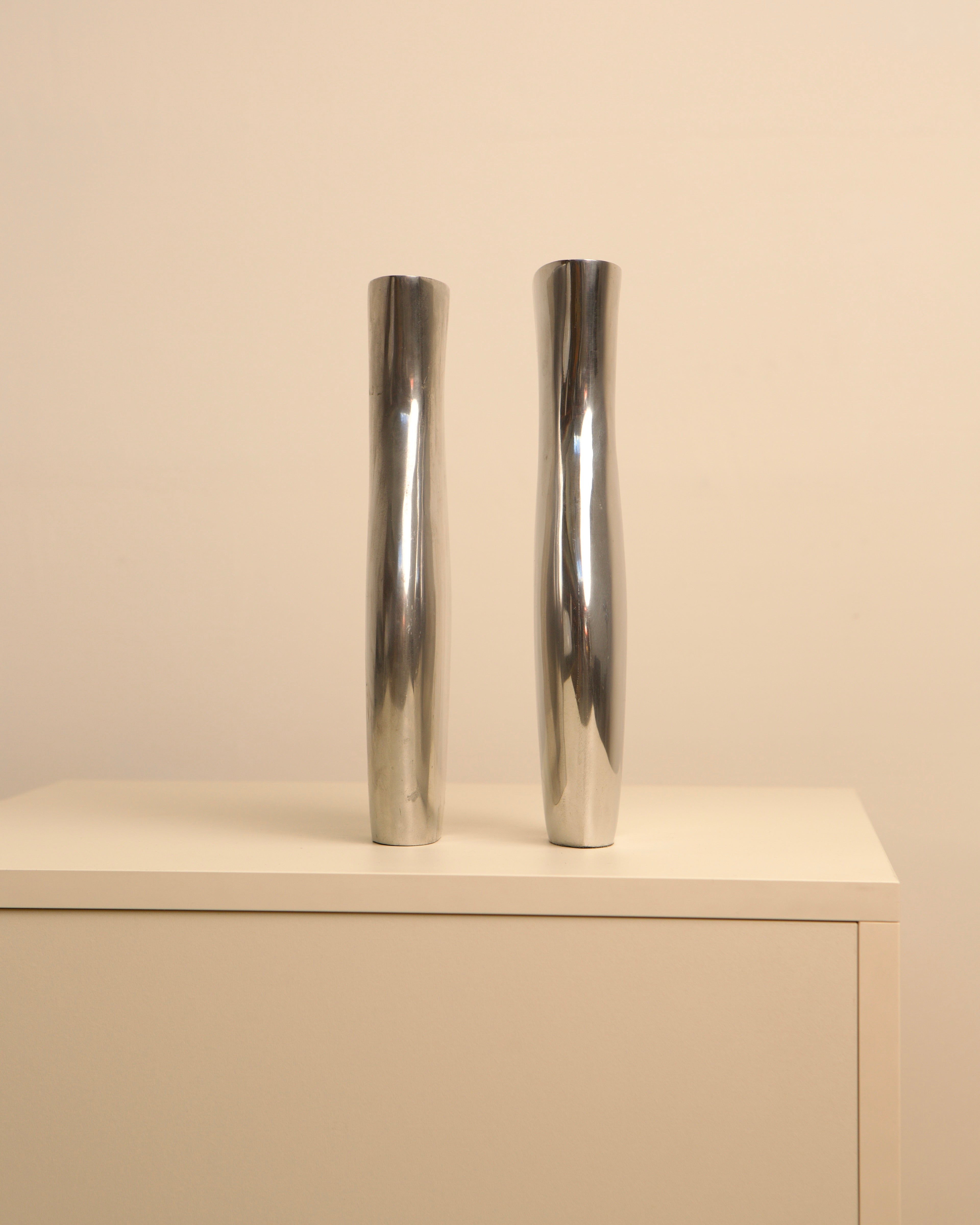 Pair of Italian aluminum Dame vases displayed on white shelf