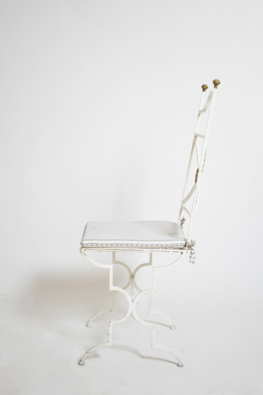 A side-view photo shows a Barracuda Interiors Set of Four White Wrought Iron Chairs (1940s) with high backs, cushioned seats, and brass finials against a plain white background.