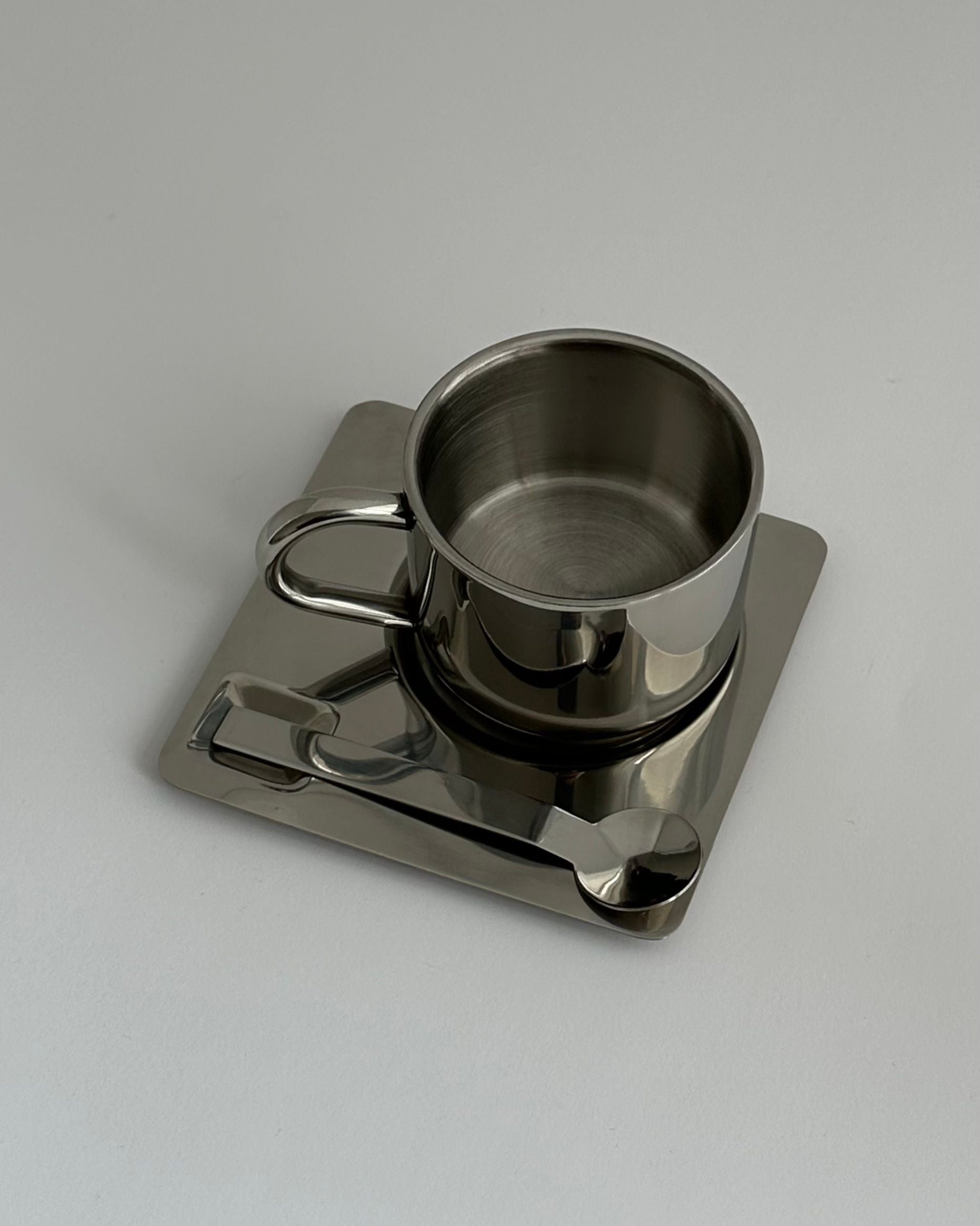'HEDONISM' stainless steel cup with saucer — lifestyle setting