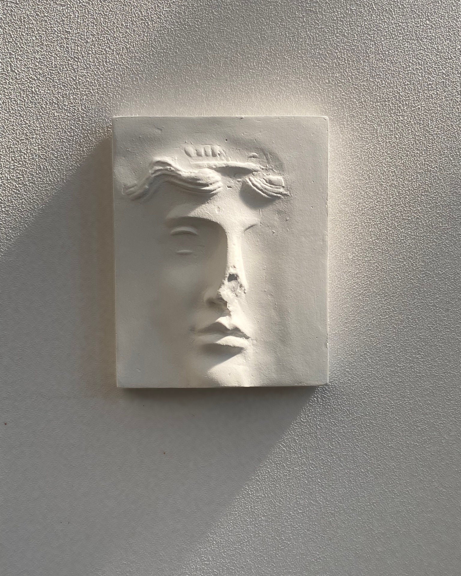 White plaster relief sculpture depicting partial female face by Marina Mankarios
