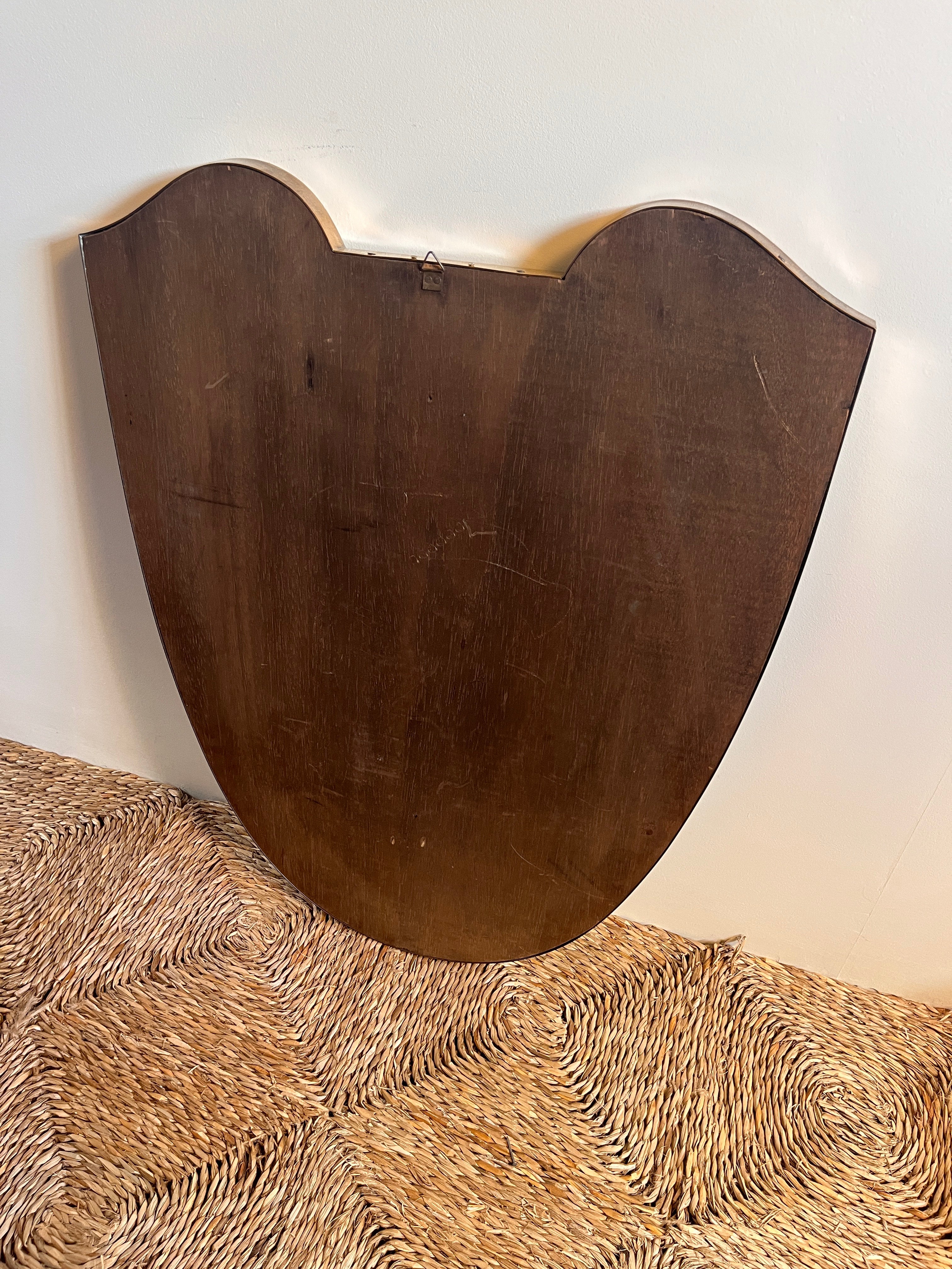 Large Midcentury Italian Brass Shield Mirror — back view against textured wall