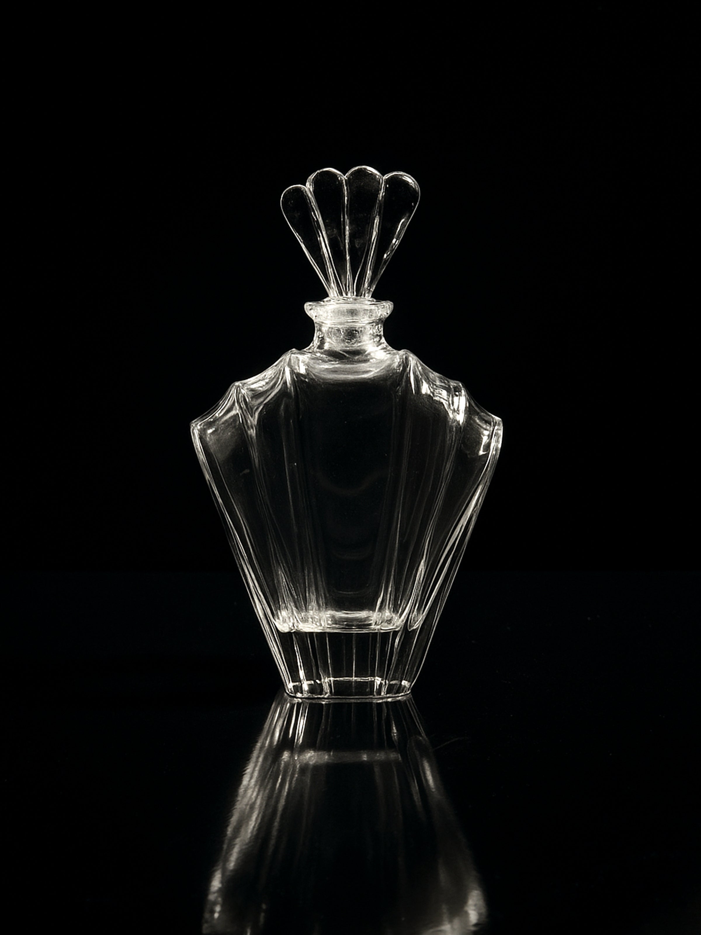 The Dodo Vintage Italian crystal Glass Art Deco Decanter from the 1980s, featuring a decorative fan-shaped stopper, is shown empty against a black background with its faint reflection visible below.