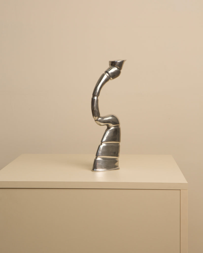 Chrome twisted candleholder with sculptural spiral form on shelf