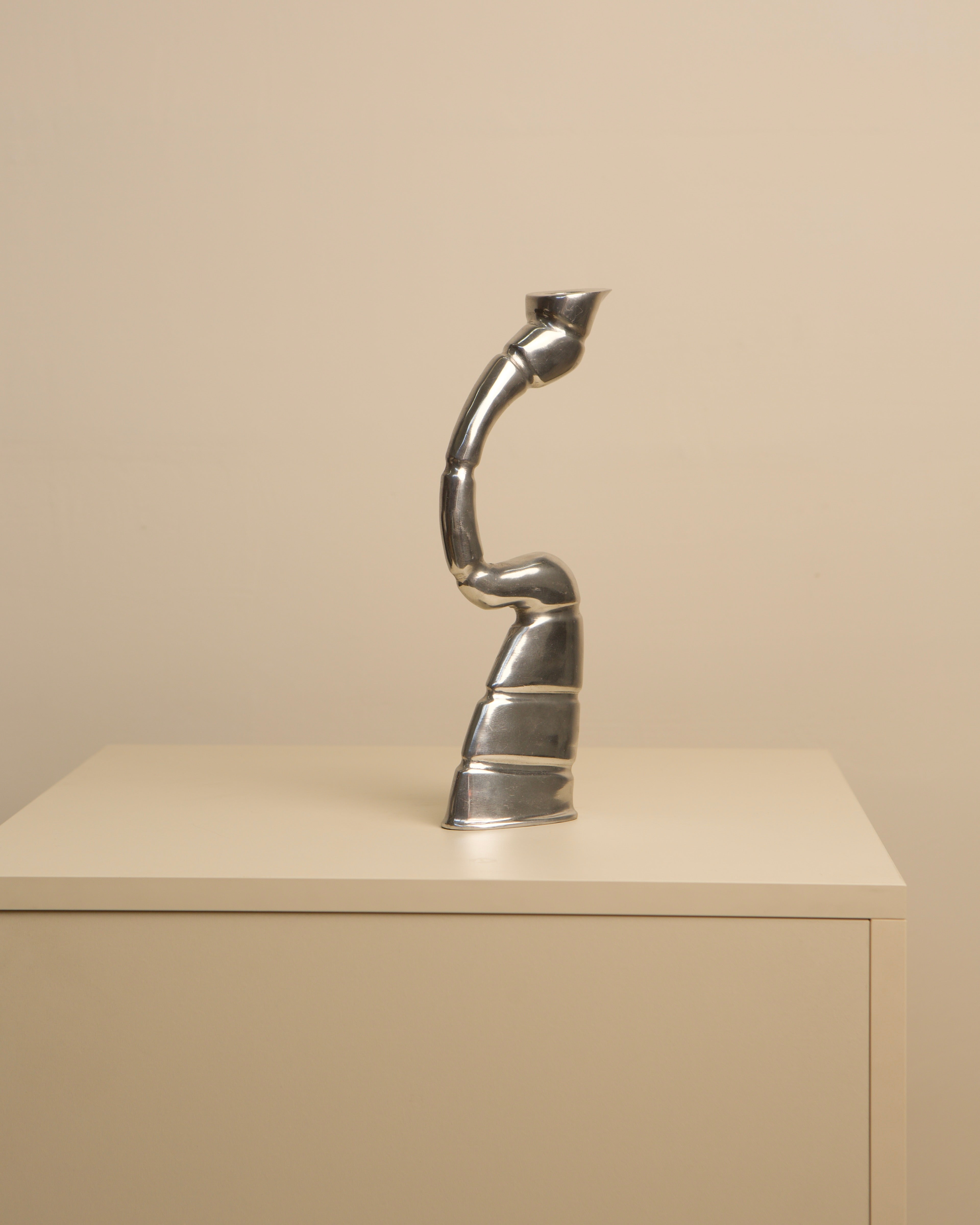 Chrome twisted candleholder with sculptural spiral form on shelf