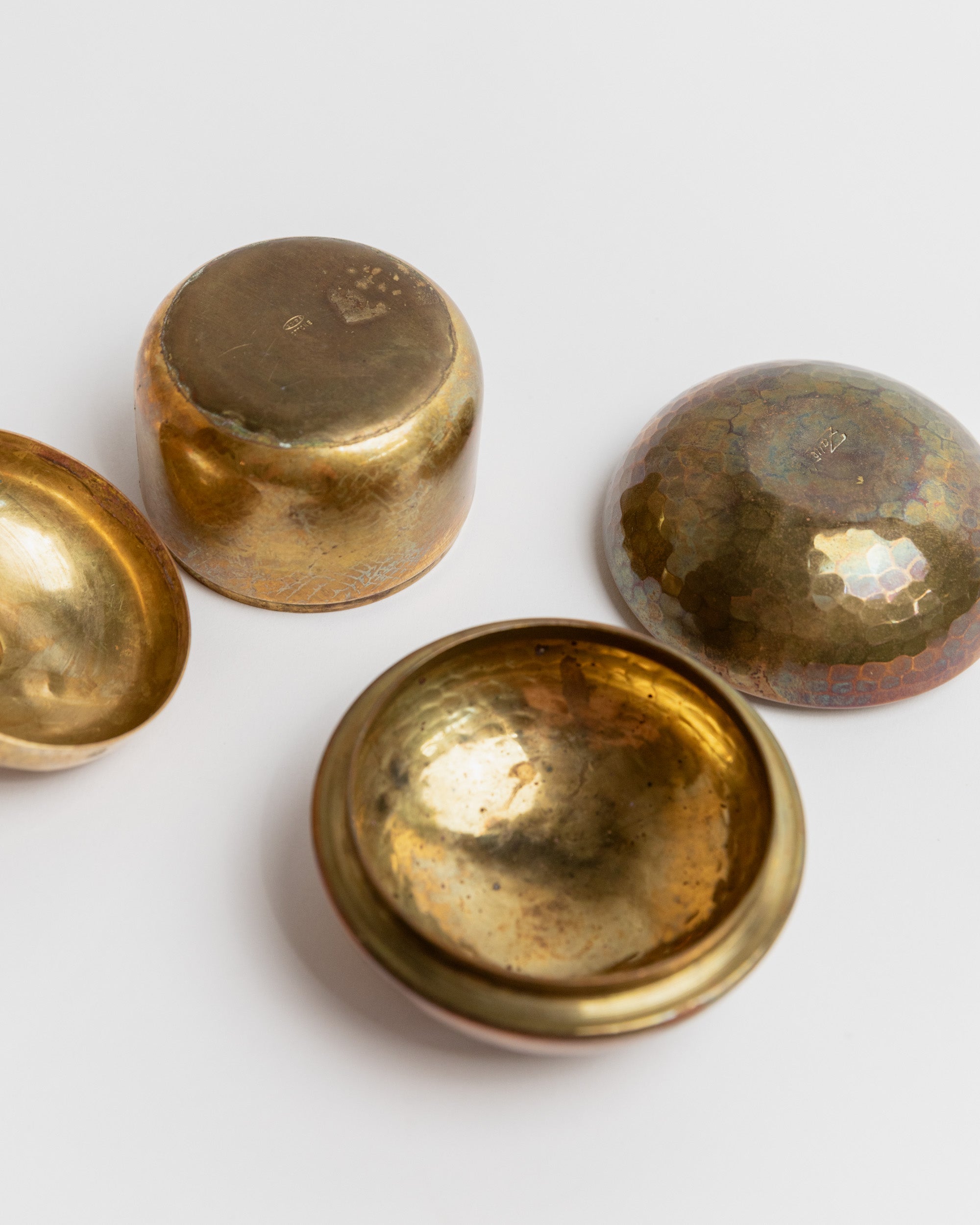 Bottom view of vintage brass tins showing patina and maker marks