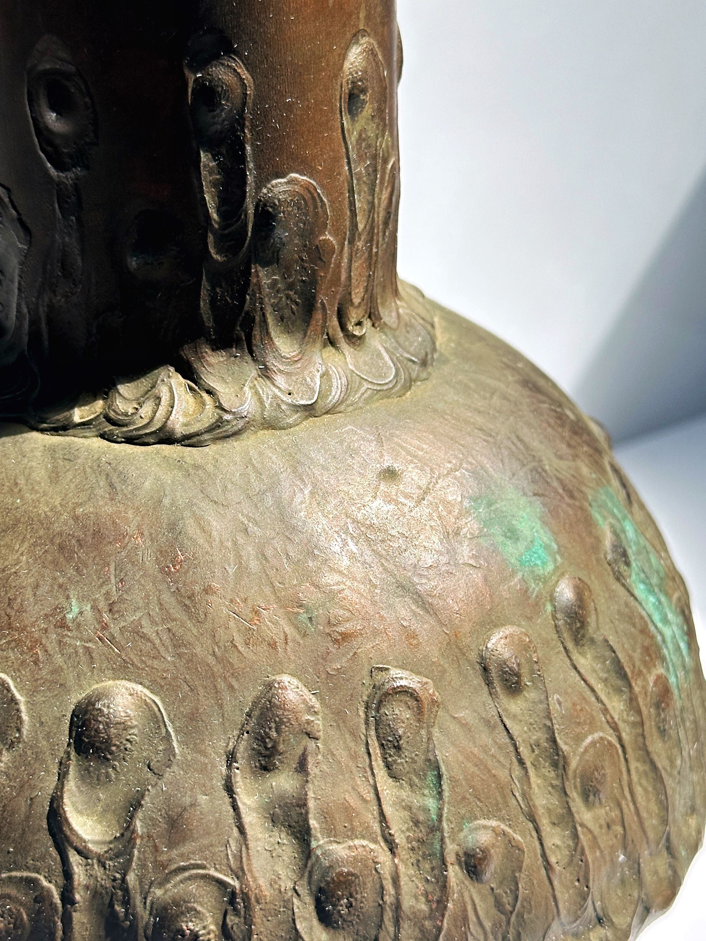 Close-up detail of copper vase showing patina and decorative motifs