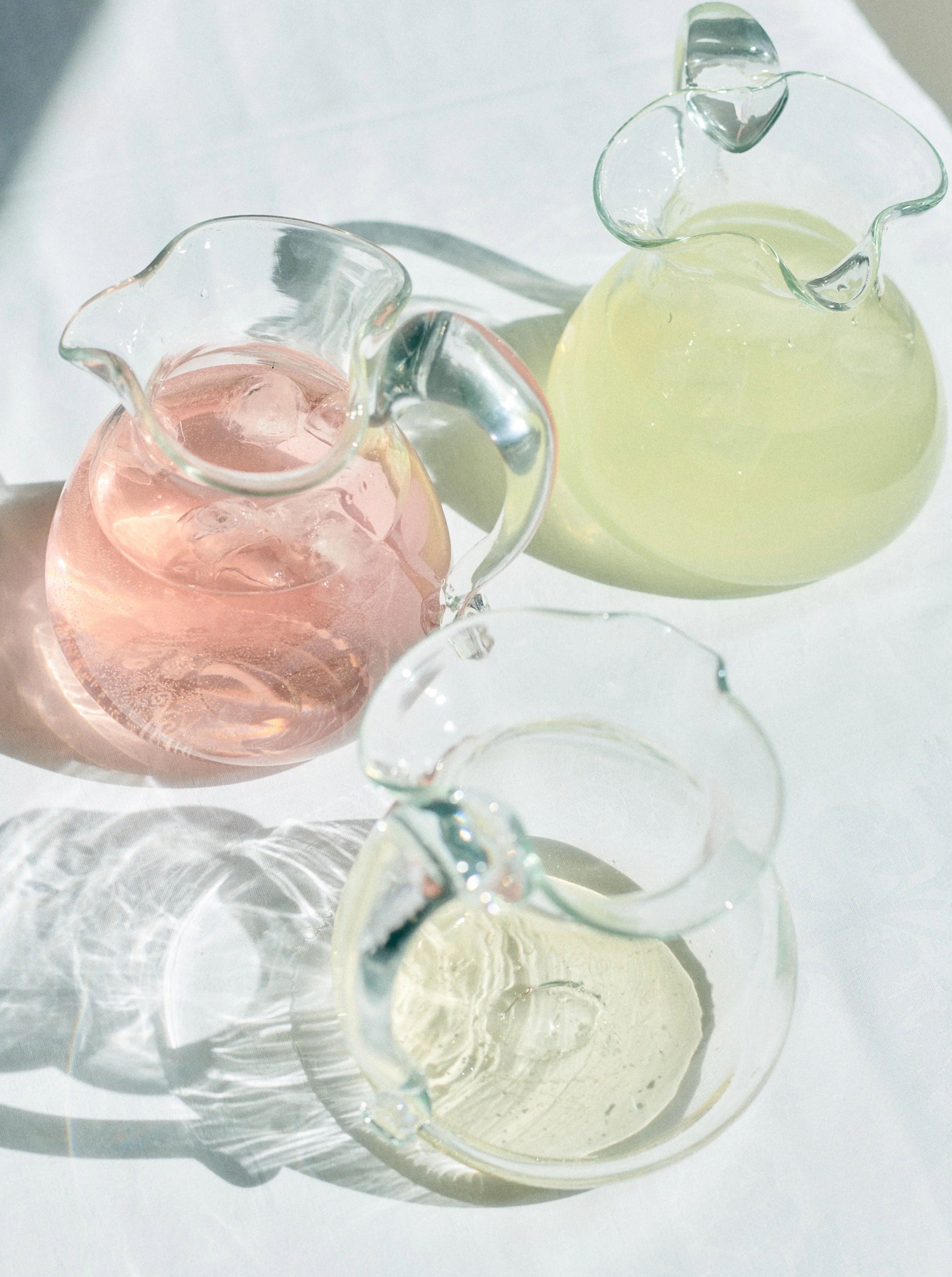 Blixen Jug — side view of three glass pitchers with colored liquids