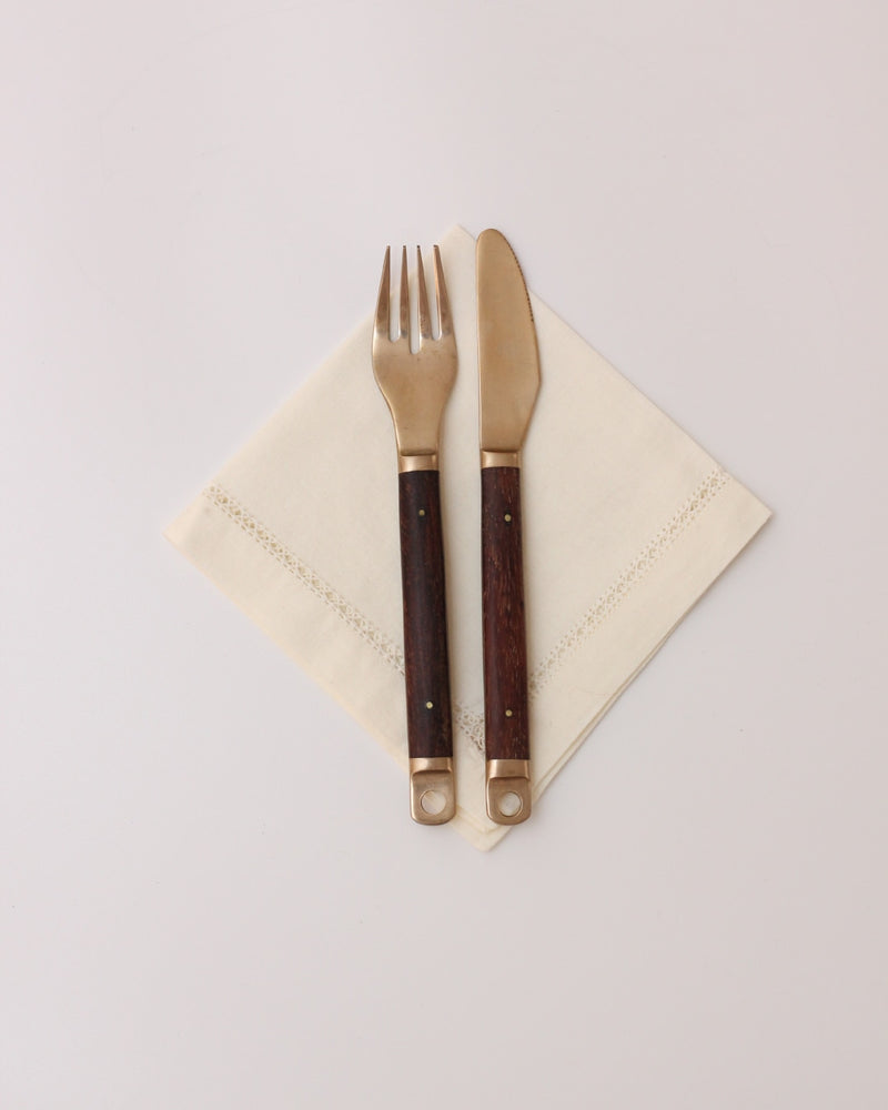 Cutlery Set — close-up of brass utensils on linen napkin