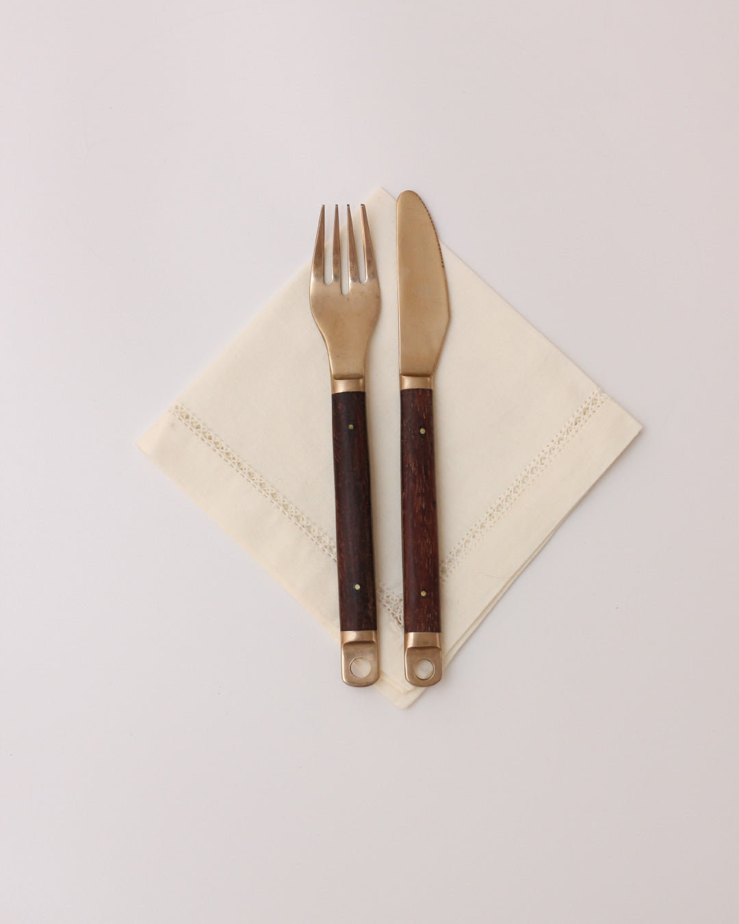 Cutlery Set — close-up of brass utensils on linen napkin