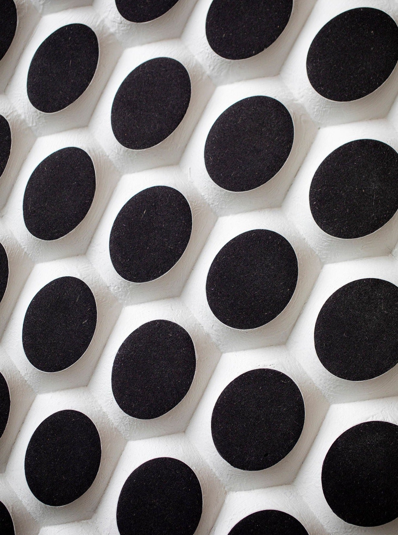 A detailed view of Studio Arno Hoogland’s Ommatidium shows a bold geometric design with large black circles on white hexagonal bases, evoking the look of an ommatidium.