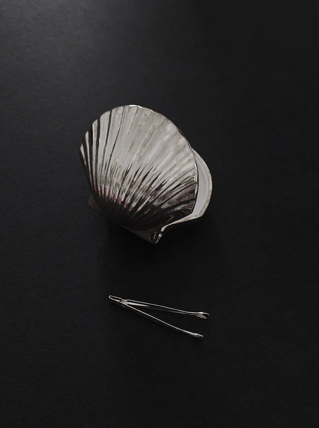 Silver-plated Shell Pill Box — angled view on dark surface with hairpins