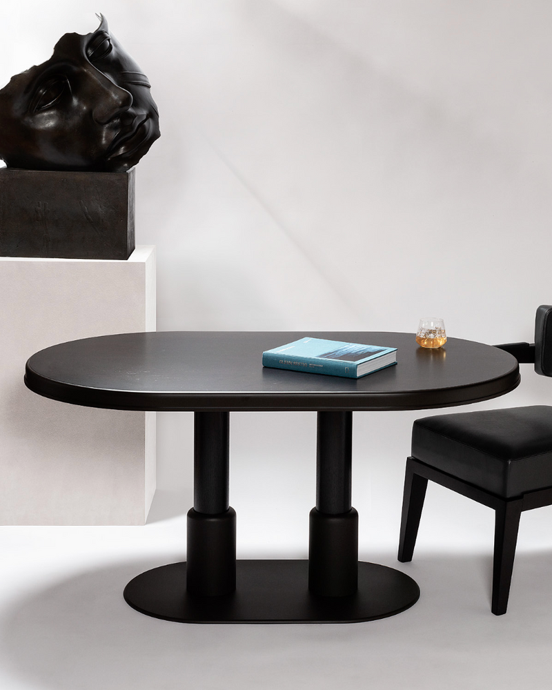 Black oval dining table with dual cylindrical base in modern interior setting