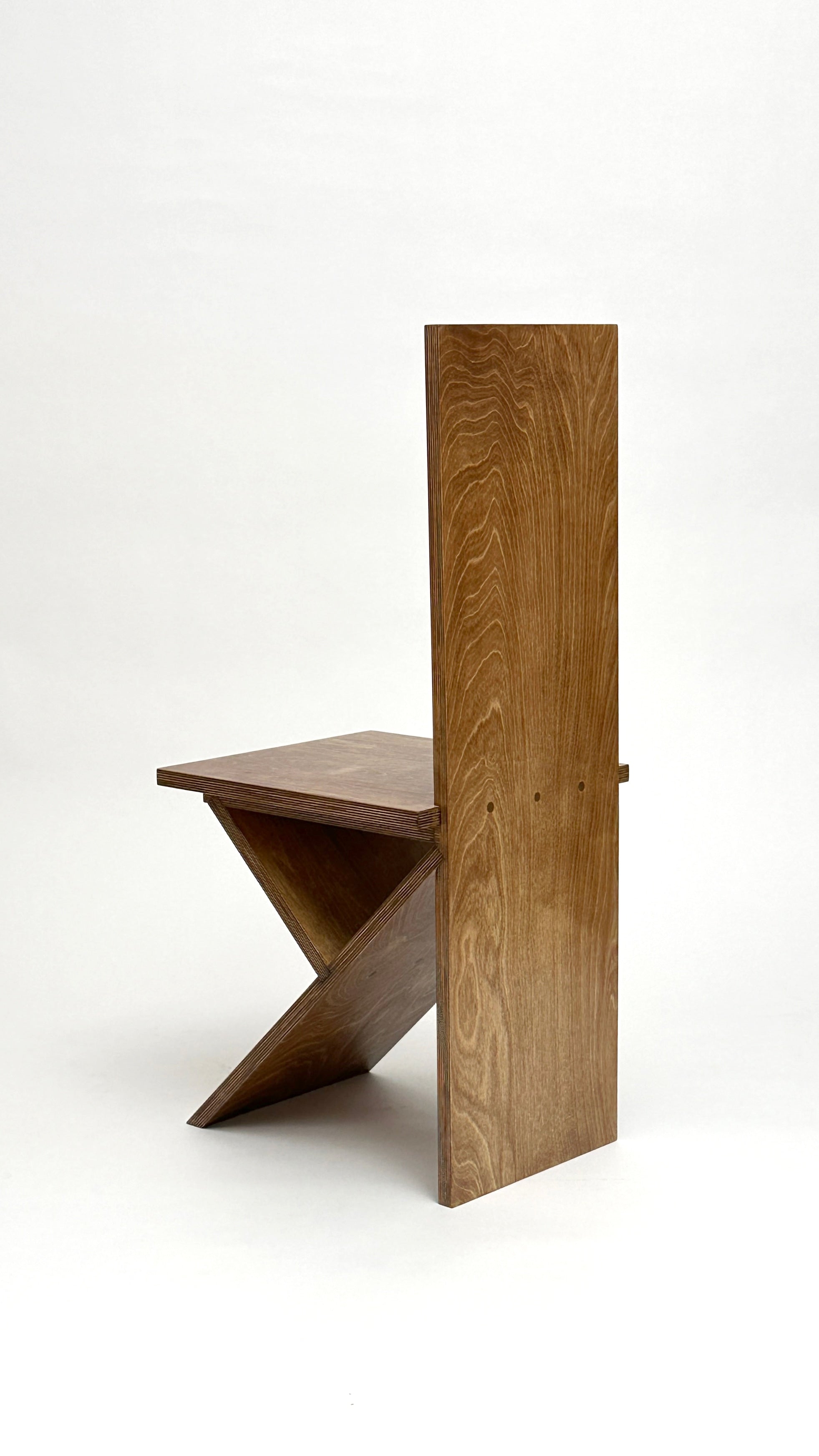 The Flat Pack Chair by Goons from GOONS features a modern geometric design with a tall rectangular backrest and intersecting angled base, crafted by a Paris design studio and shown against a plain white background.