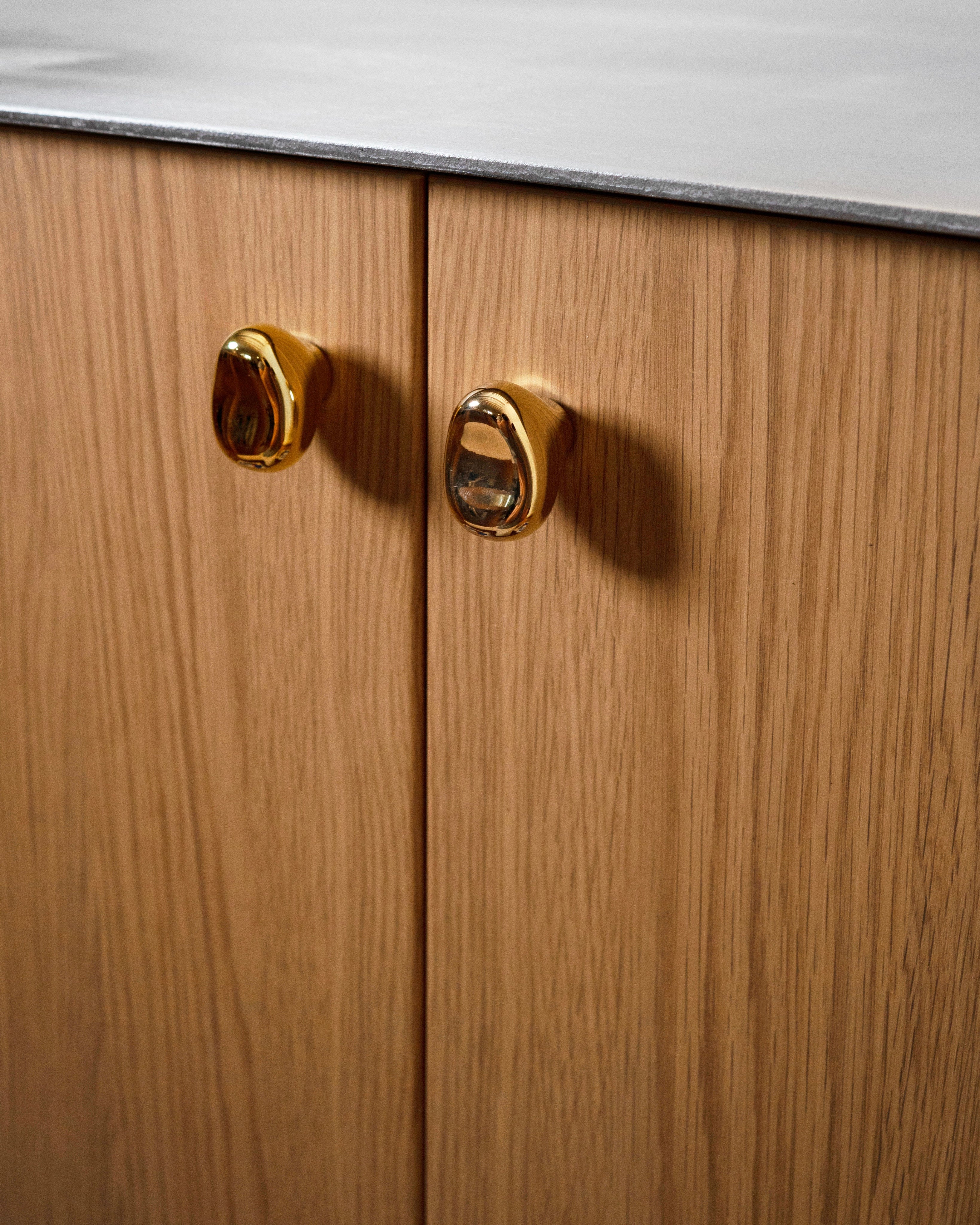 Rud Knob - Brass — top view of brass knob on wooden cabinet