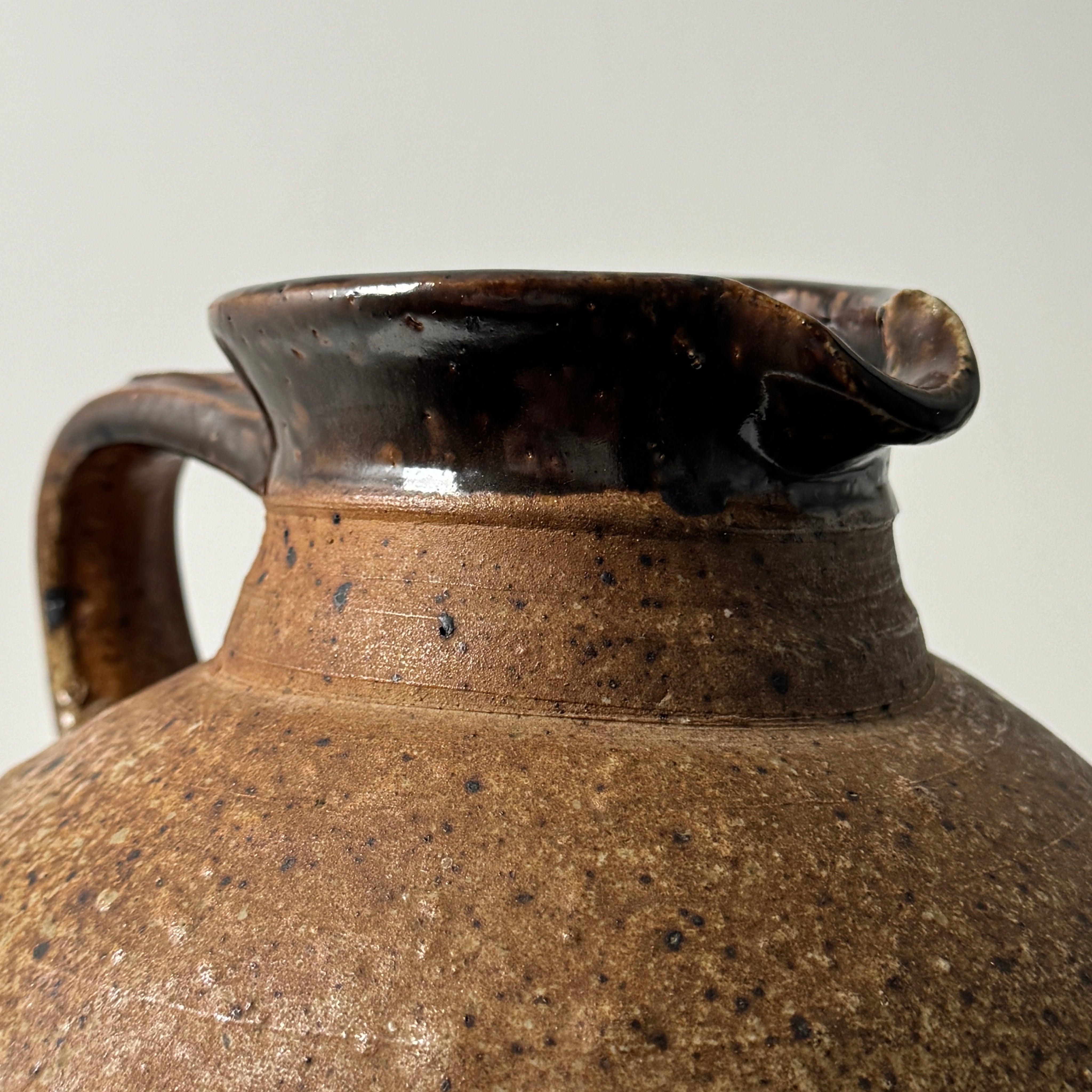 Close-up detail of glazed ceramic pitcher spout and handle