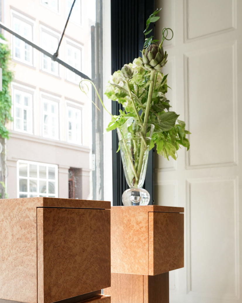 EDEN glass vase with green foliage on cork furniture by window