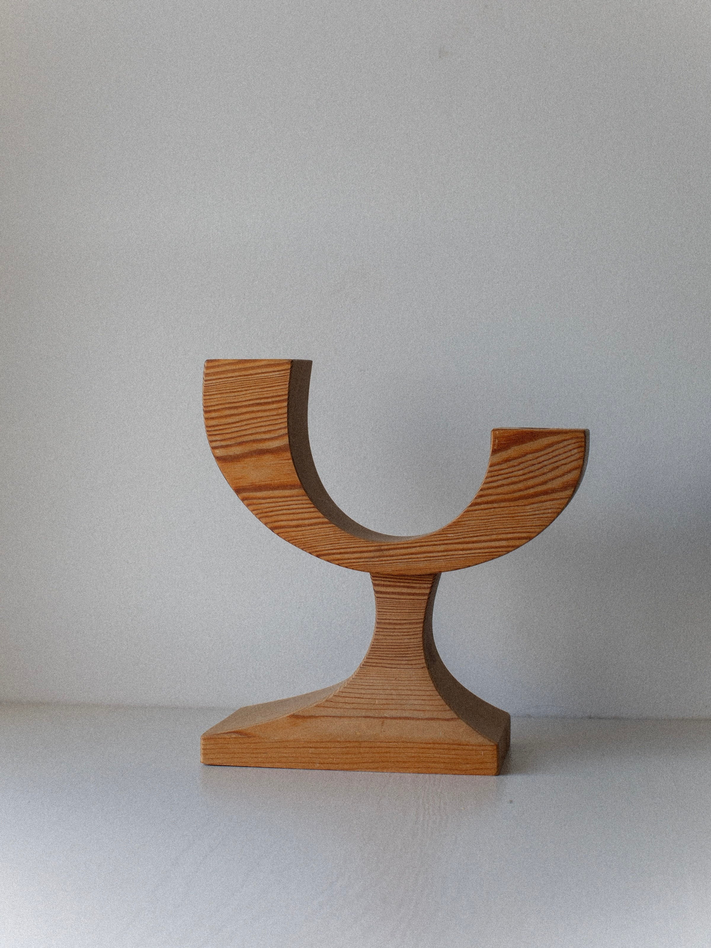 The Out For Lunch Wooden Candleholder features a vintage design with a semi-circular cutout, curved base, and rectangular pedestal, making this pre-loved decor piece an elegant accent against any light background.