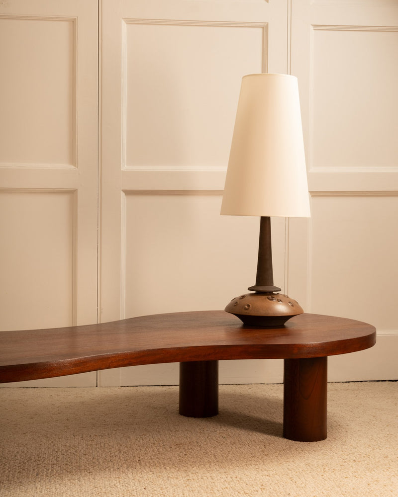 Danish ceramic table lamp with white shade on walnut coffee table