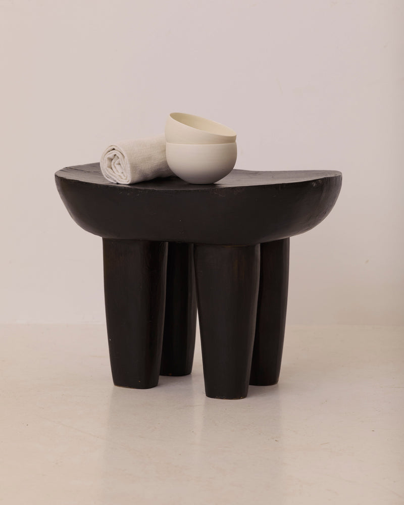 Vintage Senufo Monoxyl African Stool in Black / Wenge — close-up of black wooden surface with bowl and towel