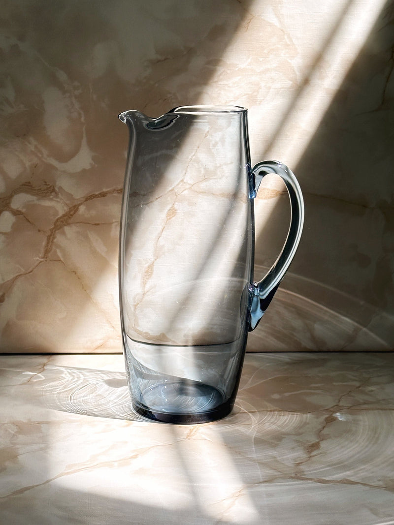 Clear glass carafe with handle and spout on marble surface