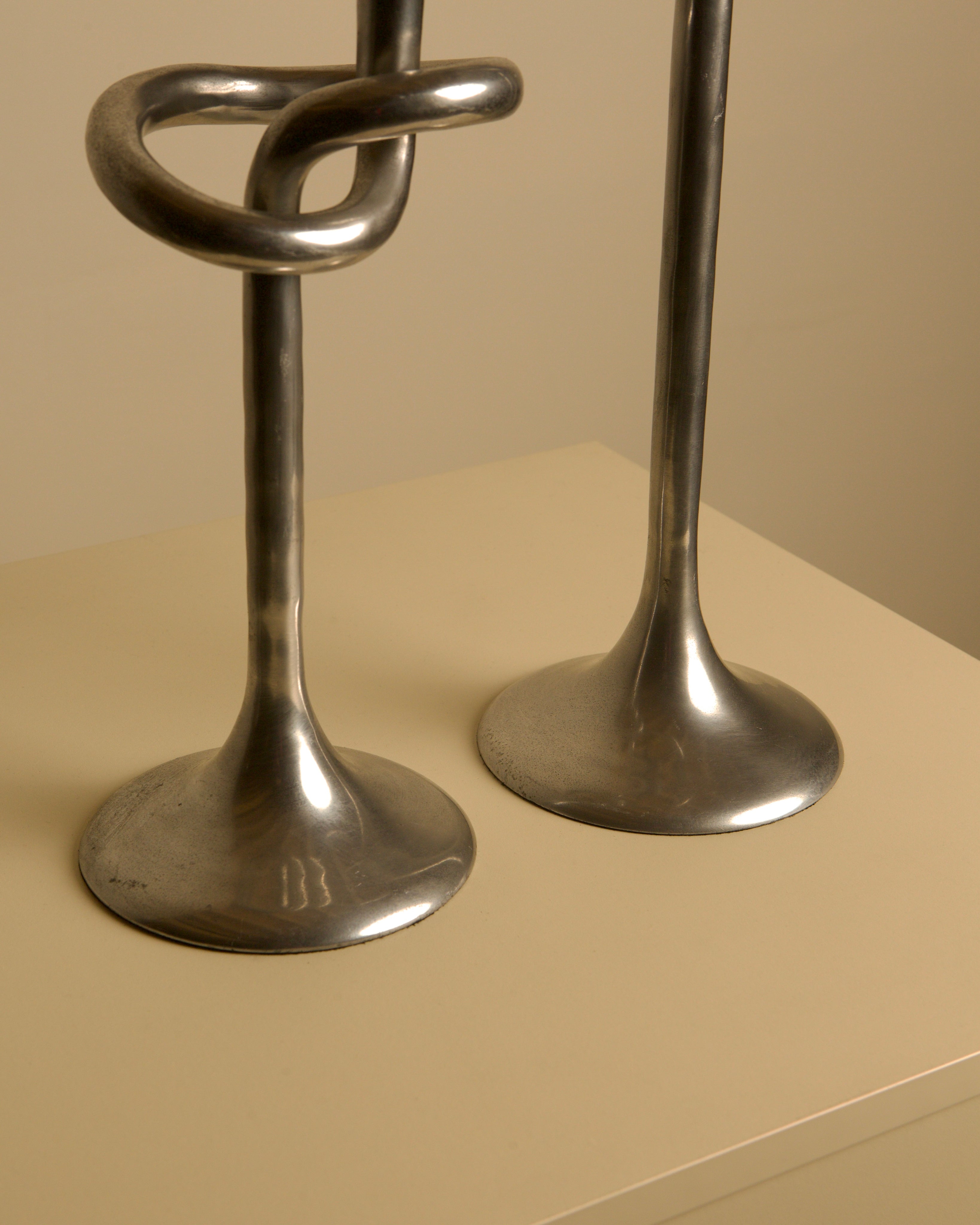 Pair of 80's Aluminum "Knot" Candleholders — side angle showing polished metal bases