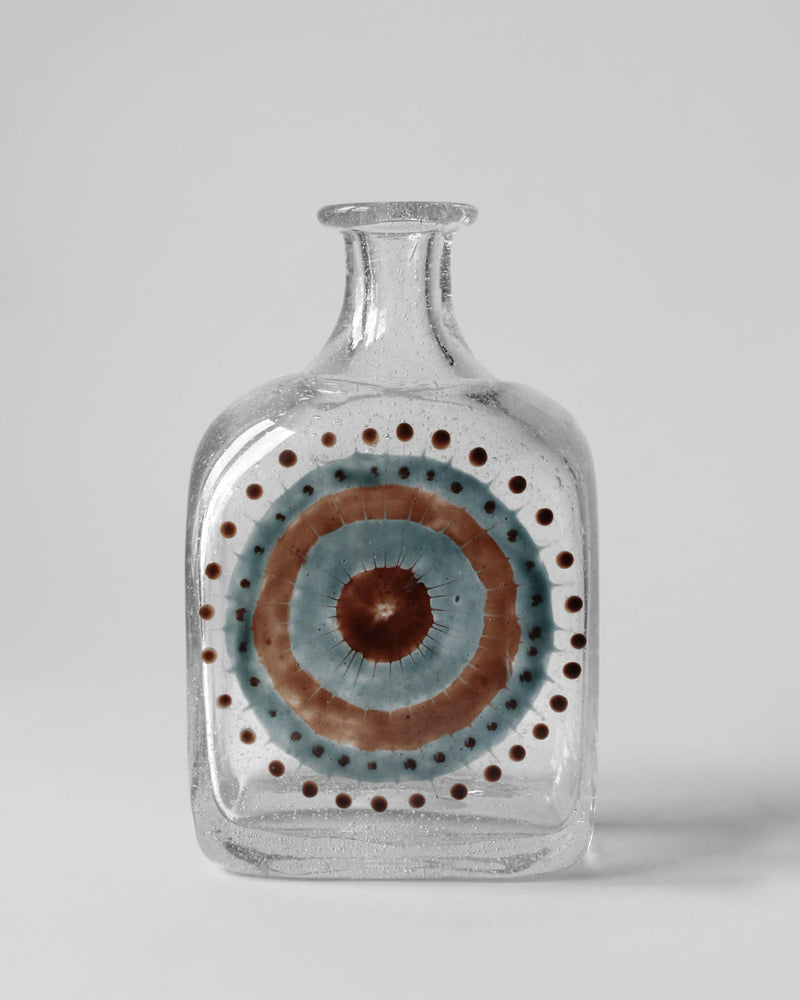 Vintage clear glass bottle with concentric blue and brown eye motif