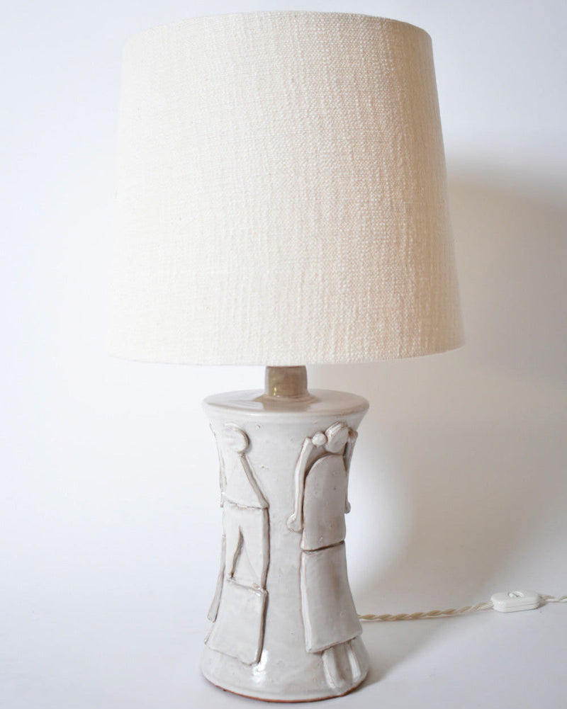 The "Kasaï" Avignon Ceramic Table Lamp by Barracuda Interiors features an off-white ceramic base with embossed abstract patterns, a textured beige shade, and a white twisted cord—ideal for minimalist, customizable spaces.