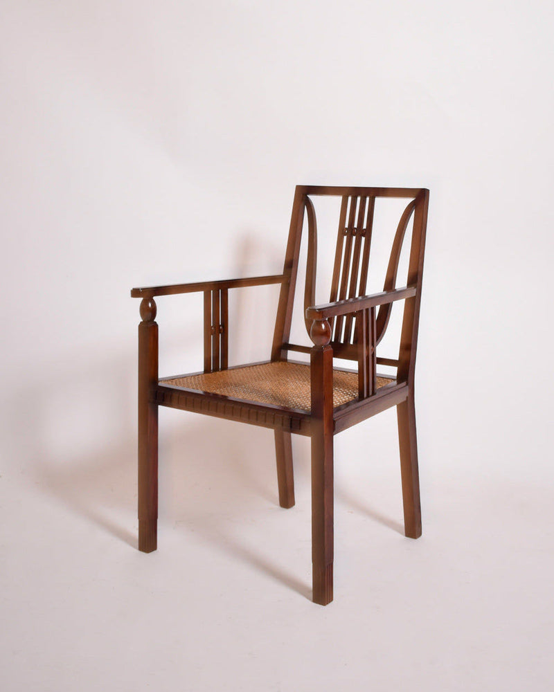 The Viennese Secession Armchair, 1910s by Barracuda Interiors features a geometric backrest, woven cane seat, straight legs, and rounded armrests. This vintage piece is set against a plain white background.