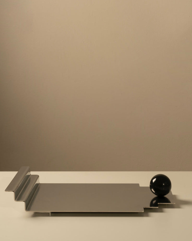 The Meridian Tray — close-up of polished metal surface with black sphere
