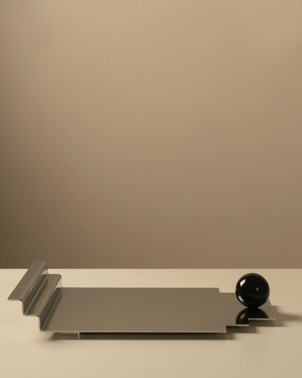 The Meridian Tray — close-up of polished metal surface with black sphere